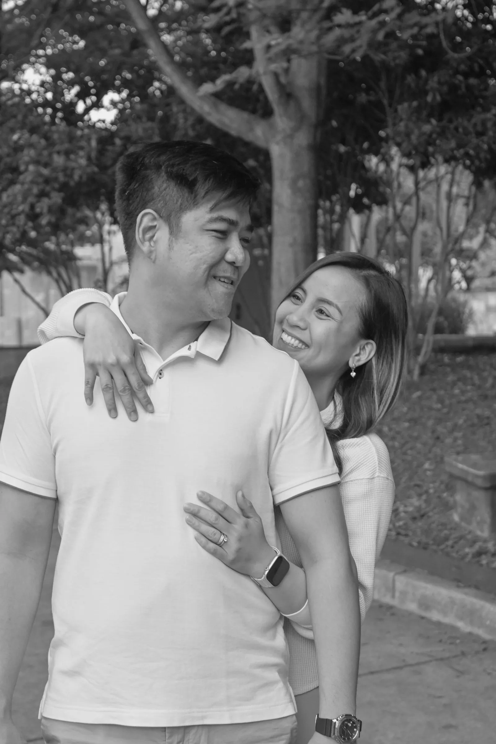 Black and white photograph of Jessica hugging Jet from behind as he laughs