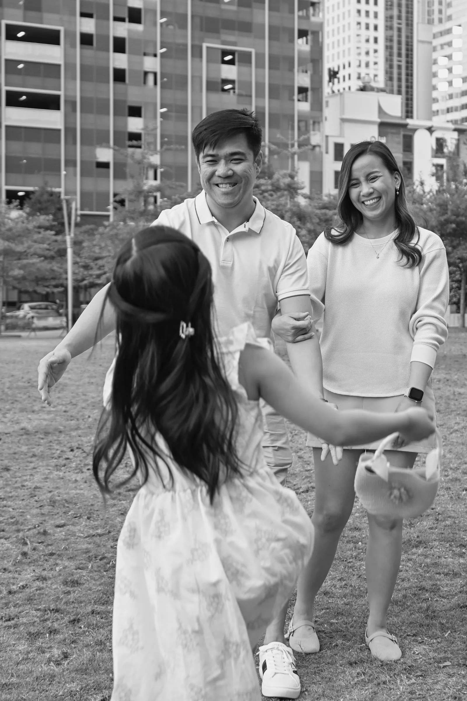 Black and white photograph of their daughter running to her parents on the lawn