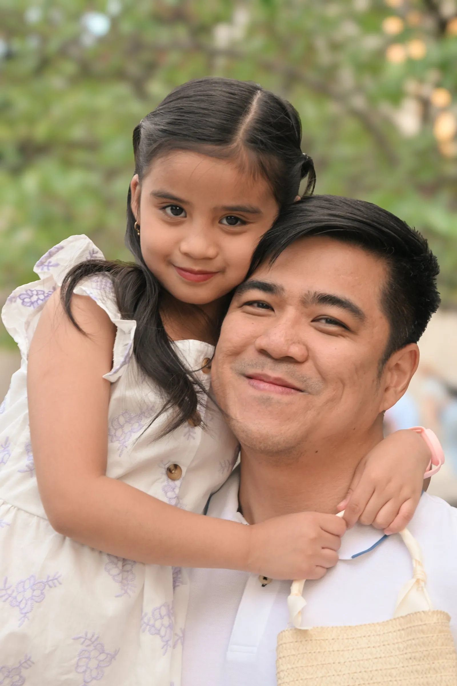 Jet grinning as his daughter wraps her arms around his neck