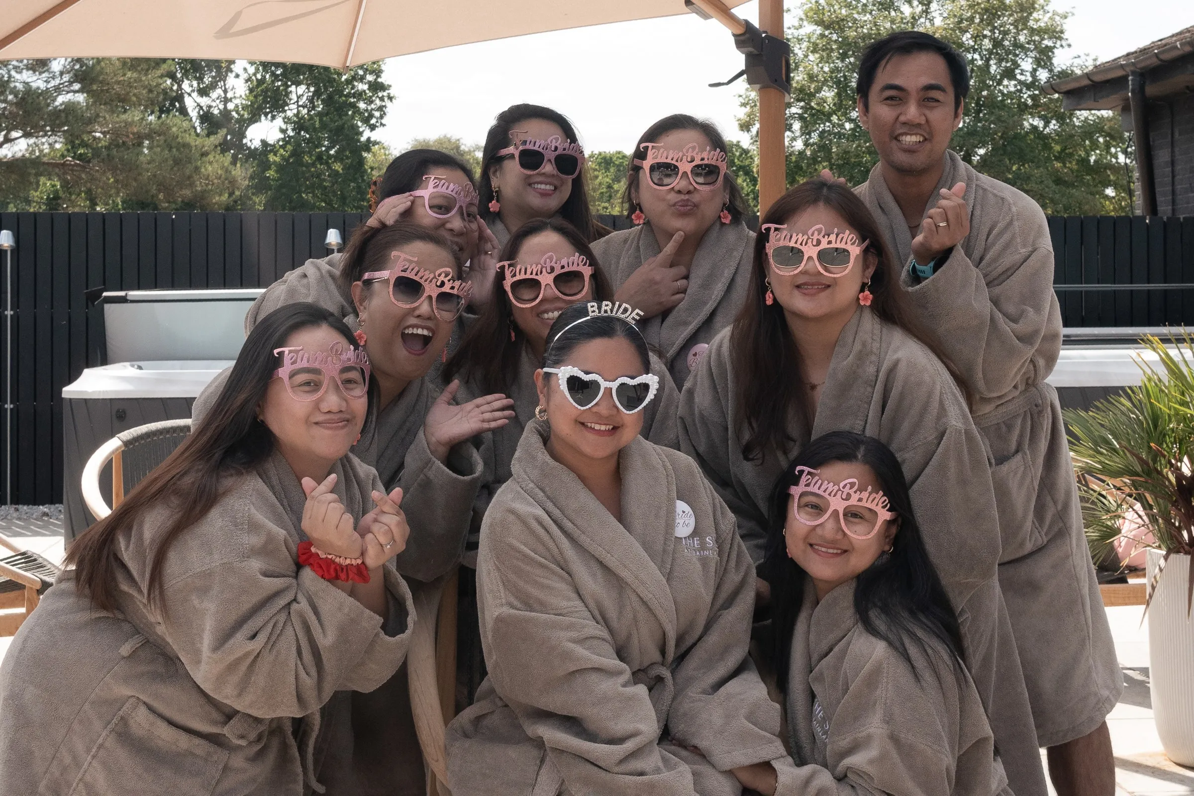 The bachelorette group in plush robes and heart shaped sunglasses smiling together