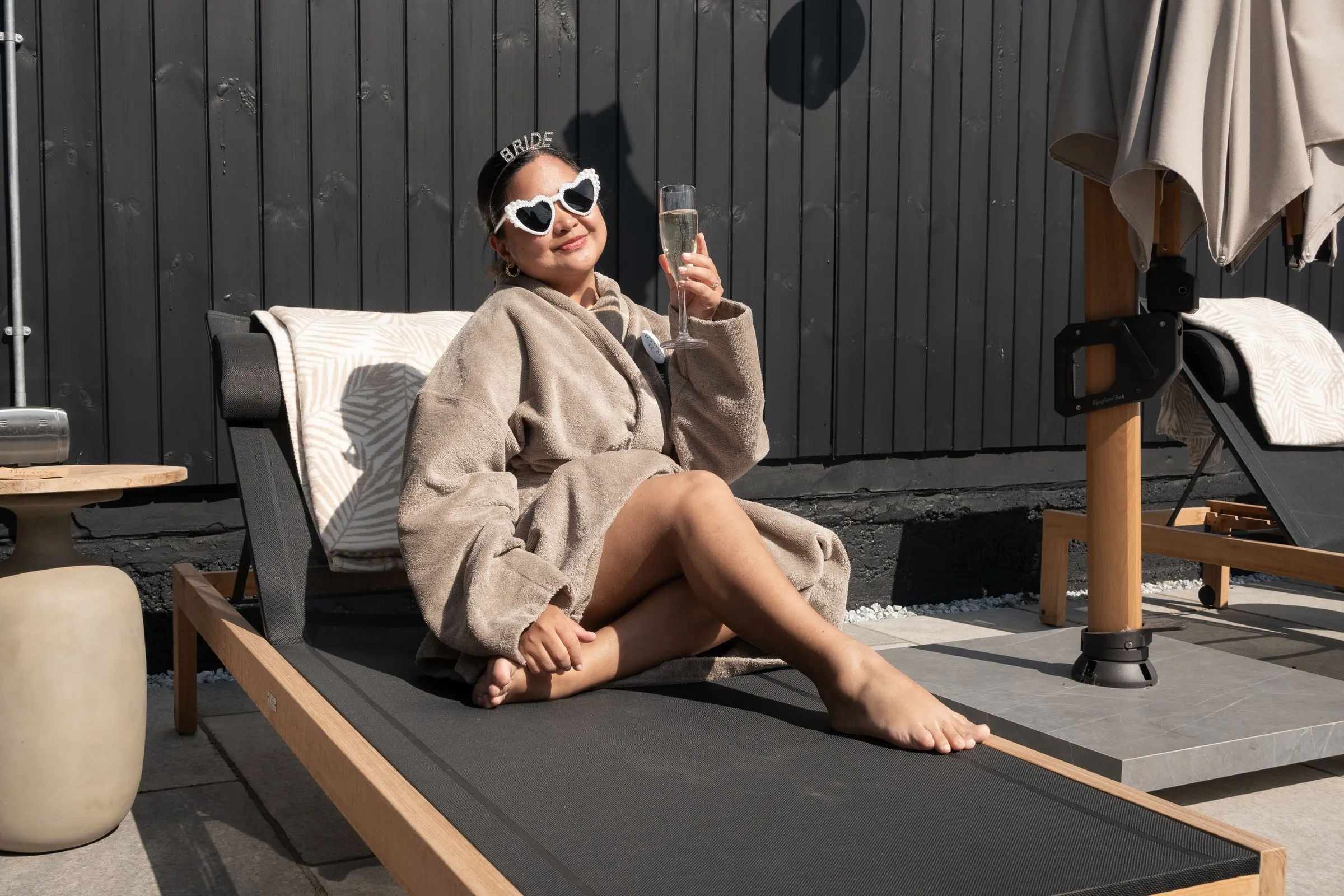 A guest in heart sunglasses toasting with champagne on a sun lounger