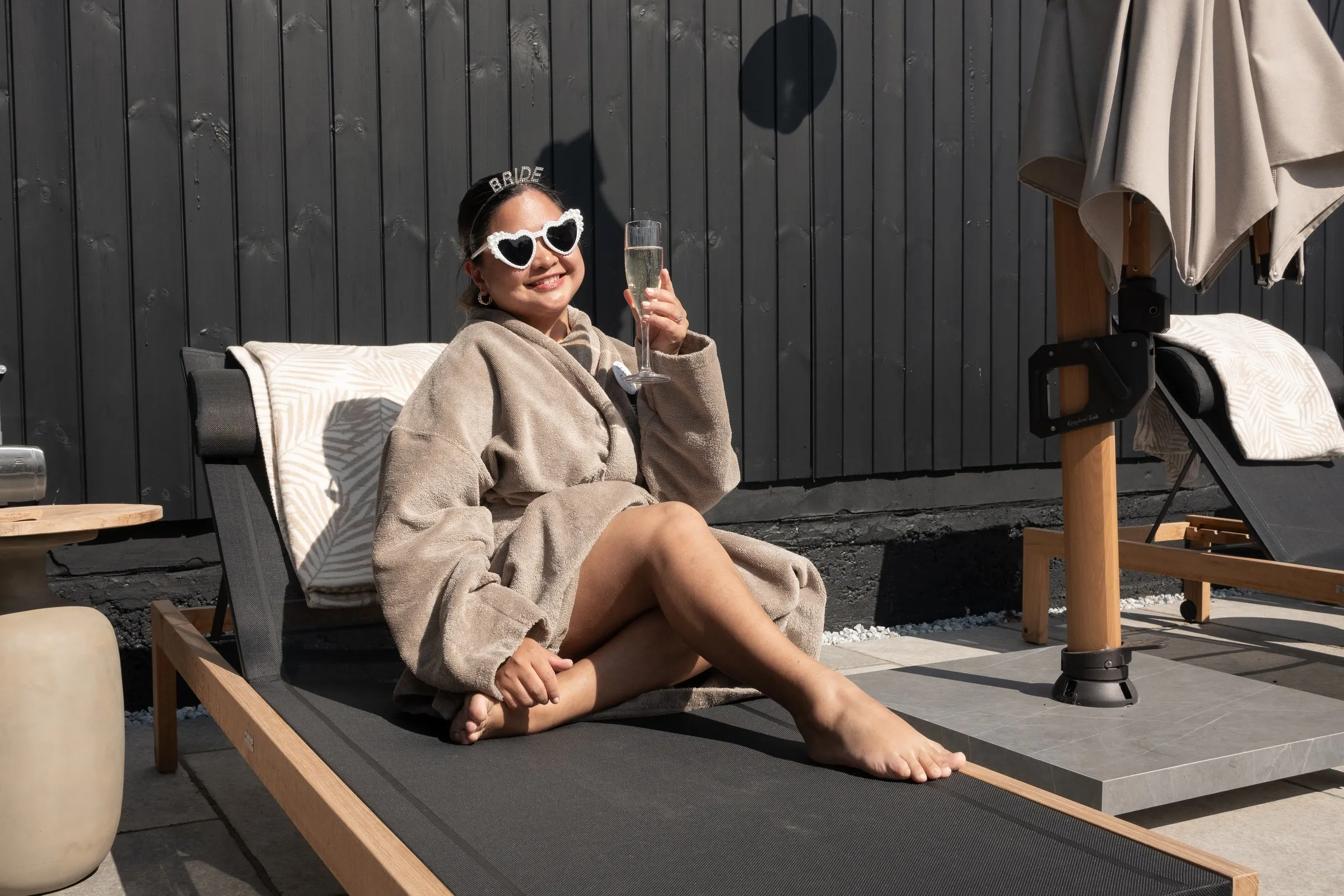 A guest laughing on a sun lounger with a glass of champagne