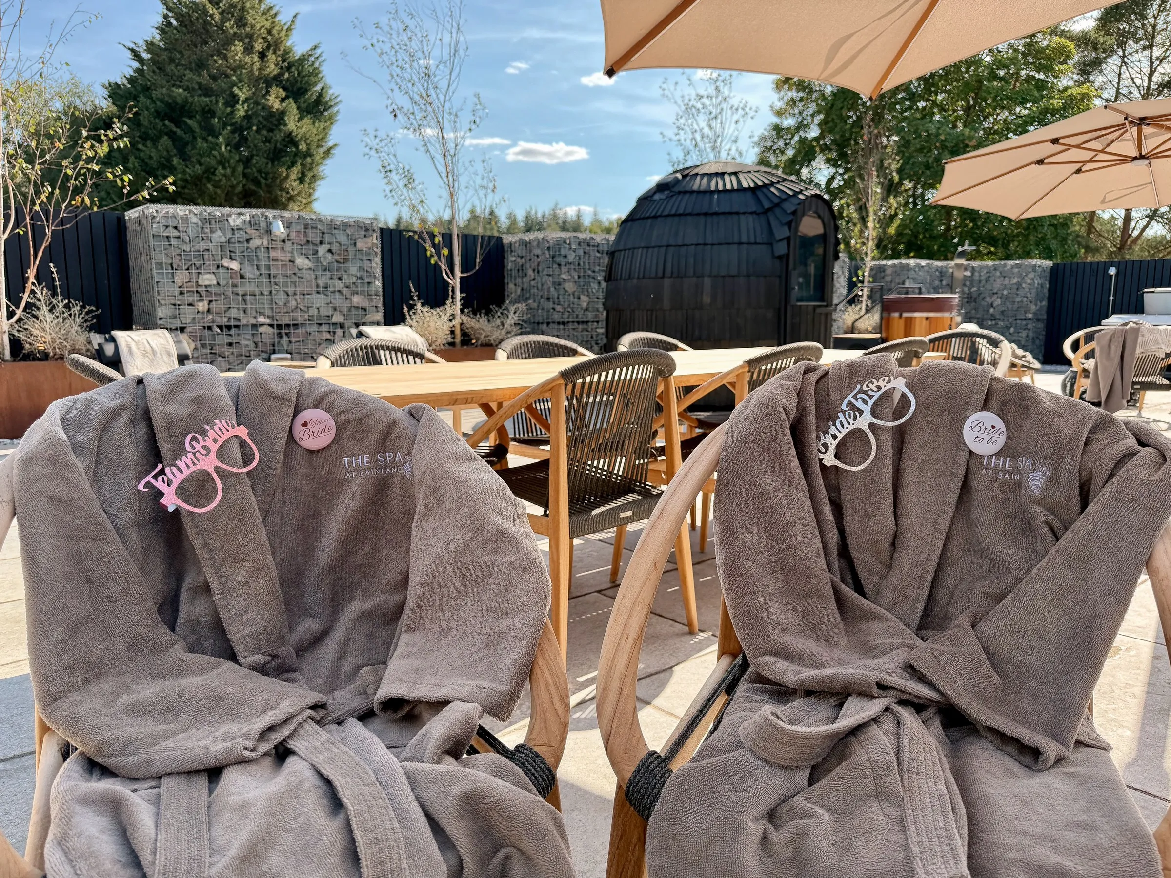 Two robes with Bride sunglasses draped over patio chairs