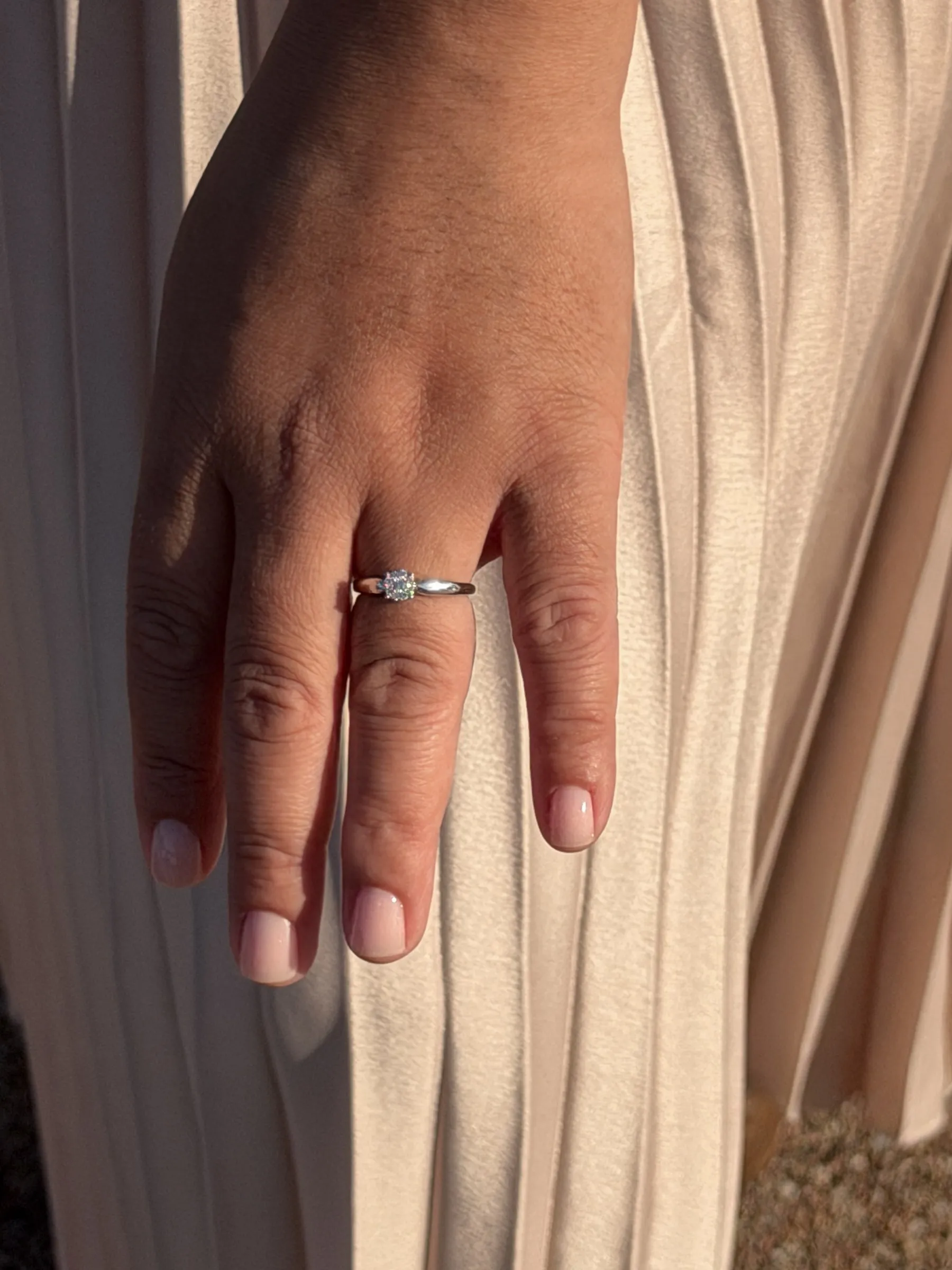Close-up of Mathelle's engagement ring against her pleated skirt