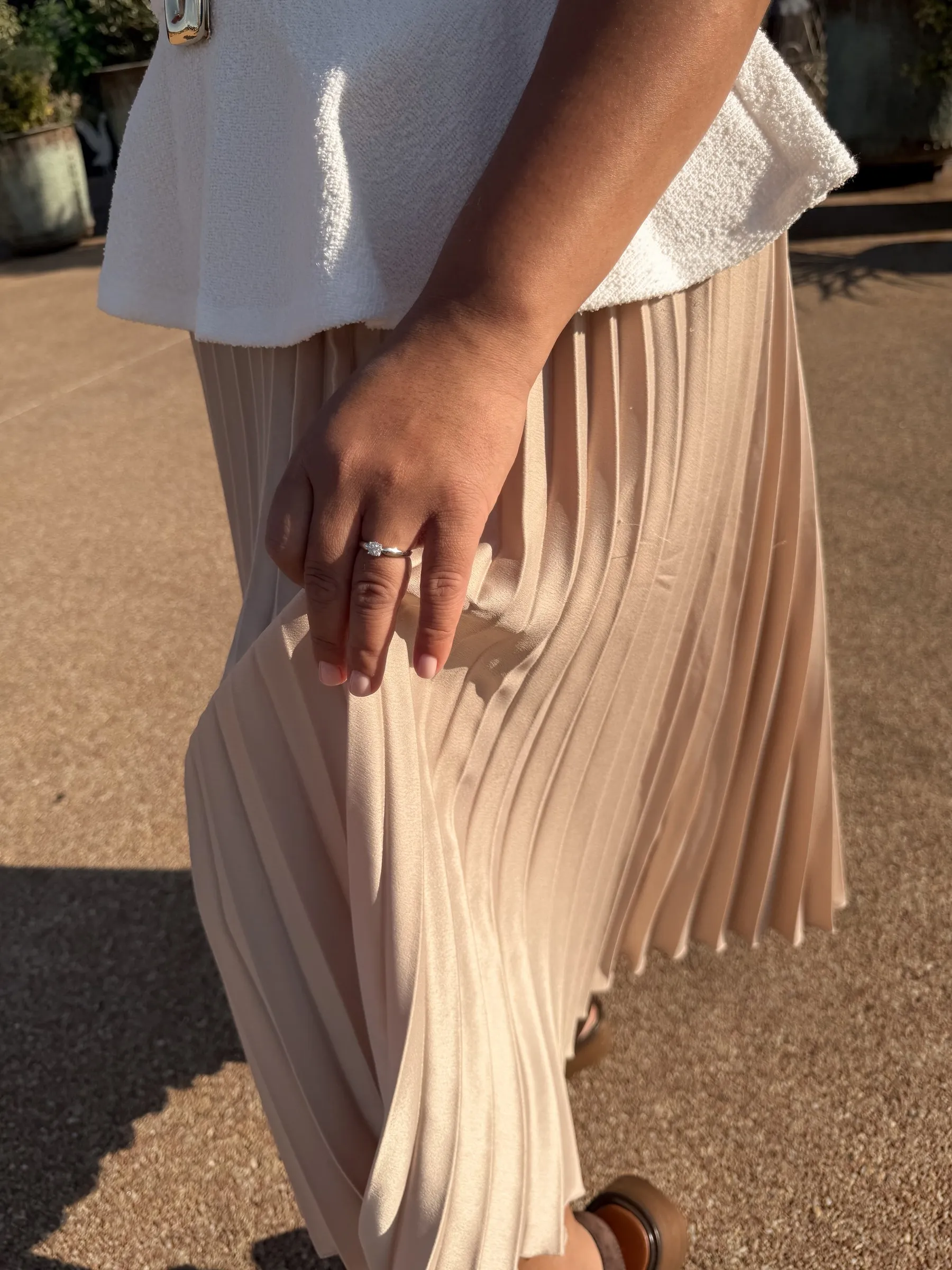 Mathelle's engagement ring and pleated skirt as she walks