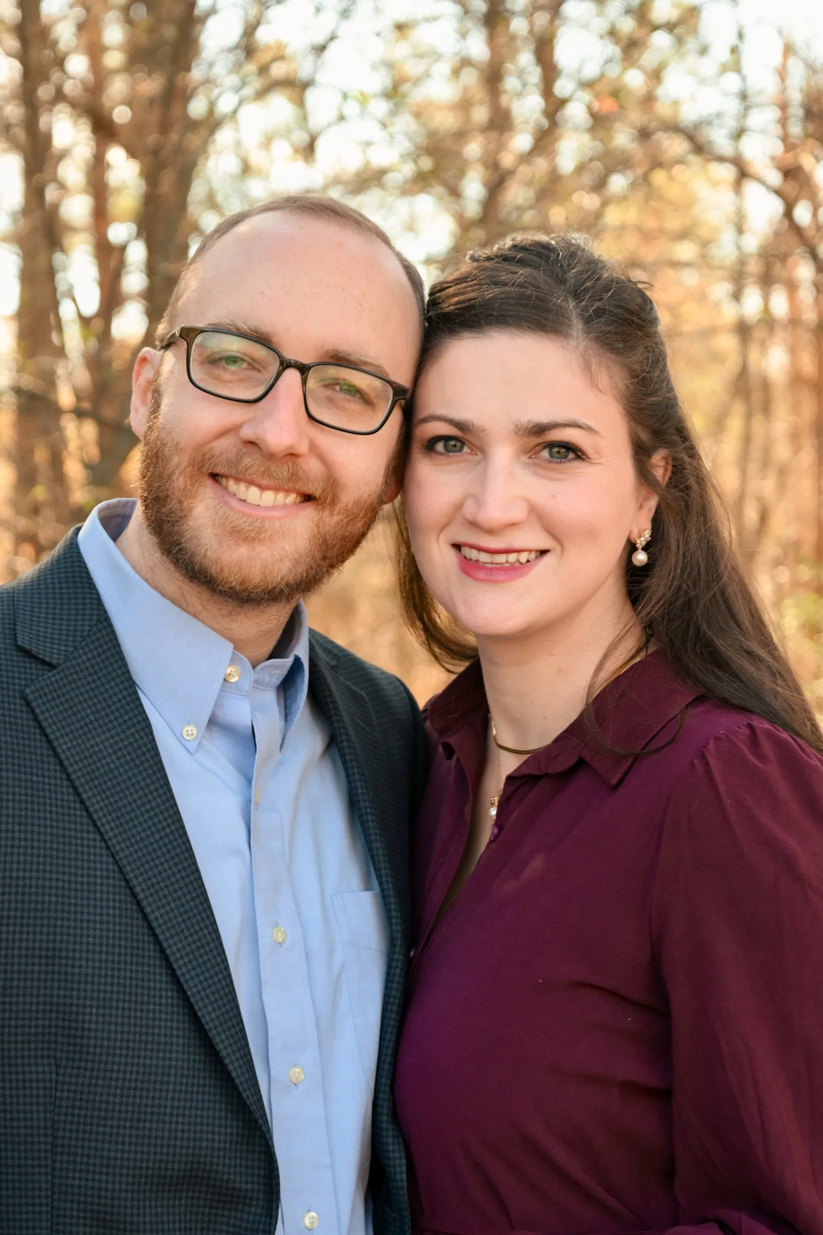 Matt and Olivia cheek to cheek, smiling at the camera against golden trees