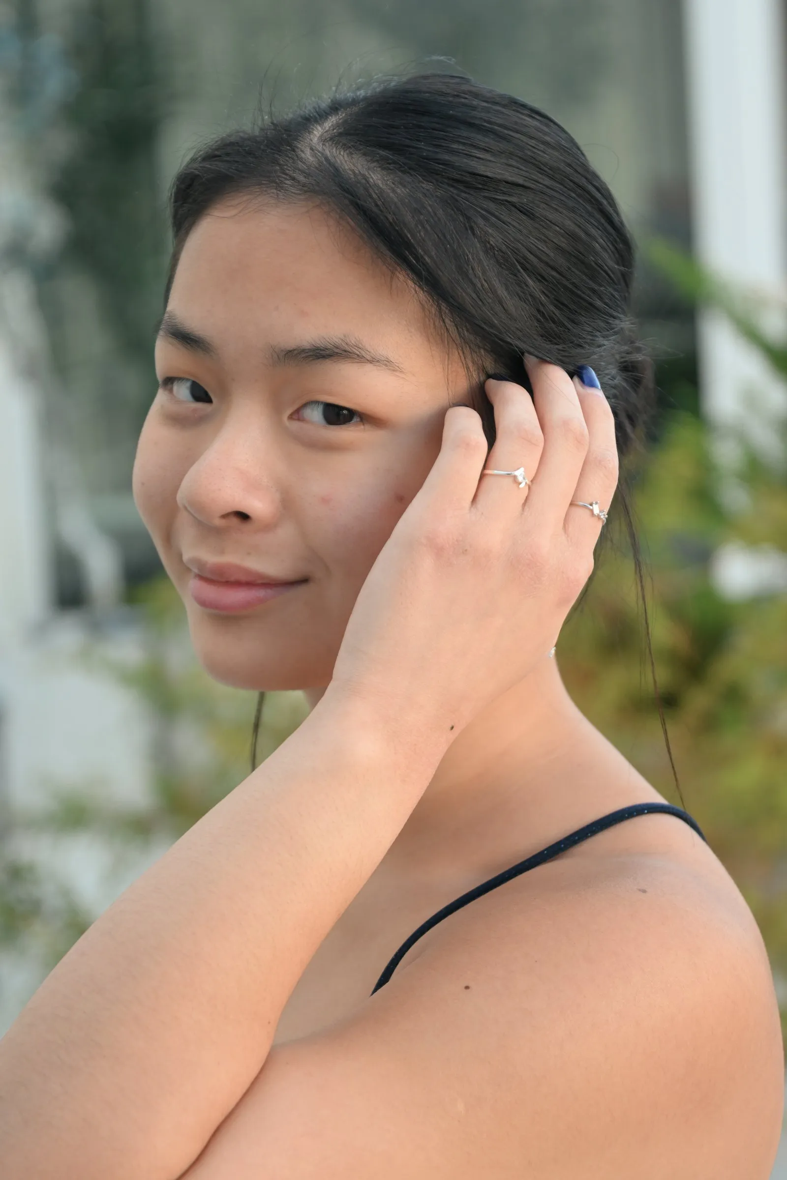 Close portrait of Meilin smiling softly, her hand tucked into her hair and rings catching the light