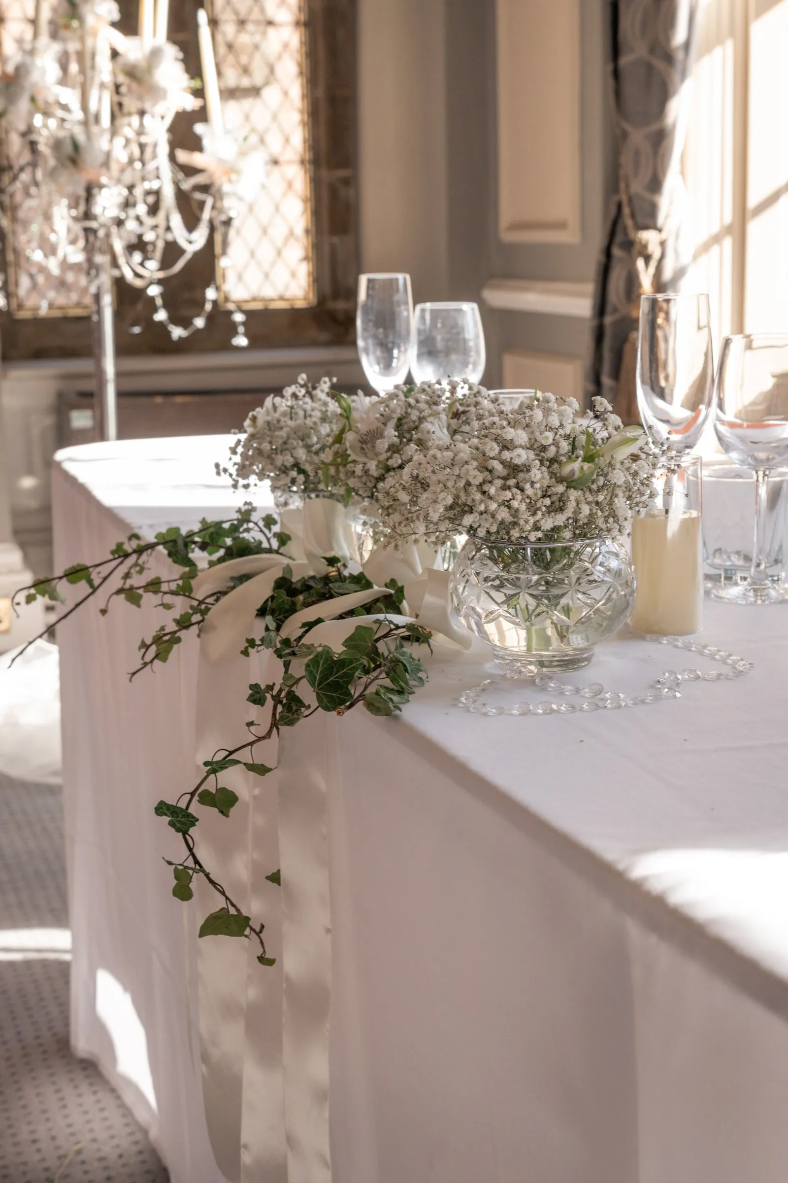 Baby's breath and ivy arrangement on the head table in soft window light