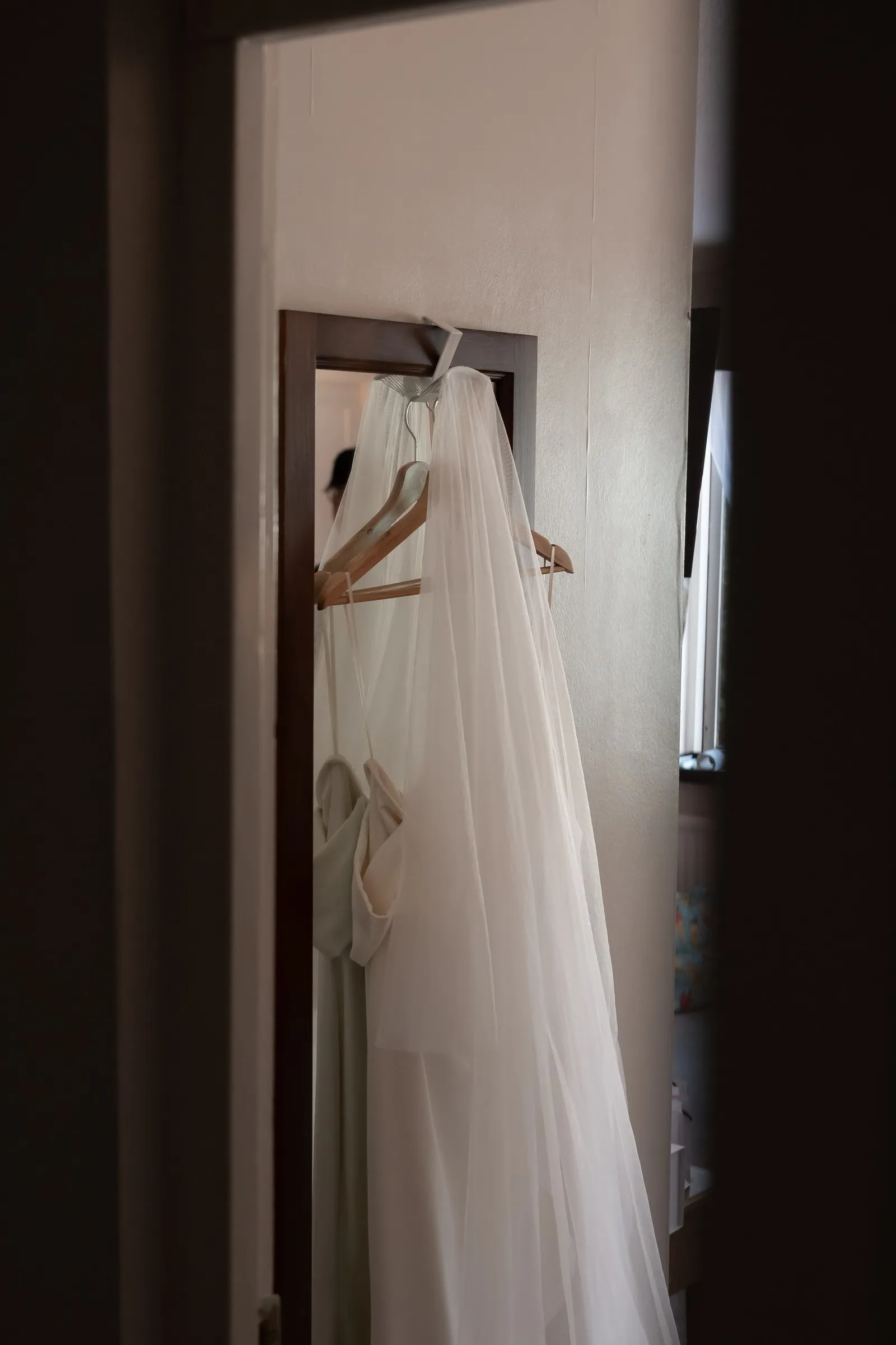 Mathelle's wedding dress hanging in a doorway