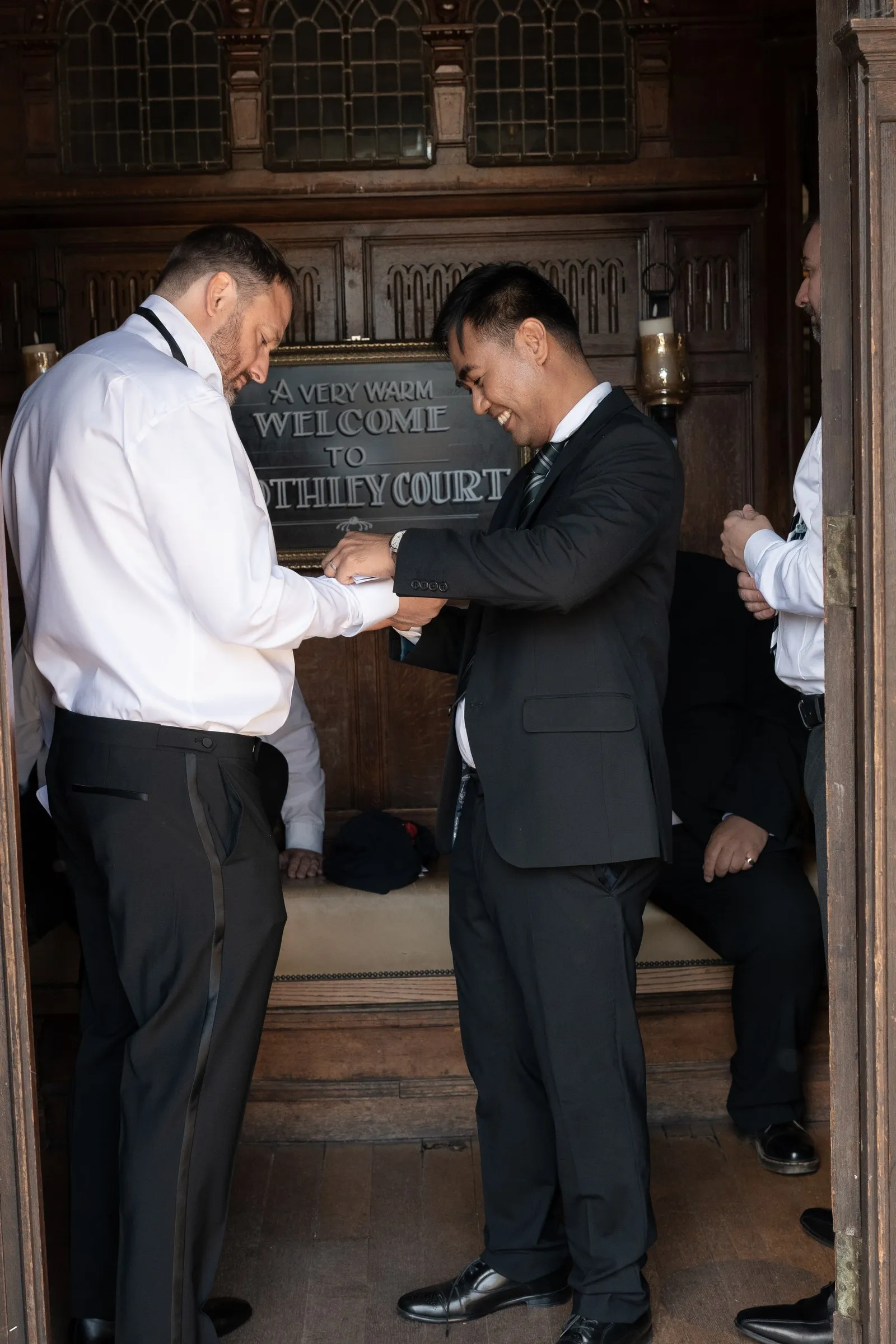 Mitch getting ready with a groomsman beside the Rothley Court welcome sign