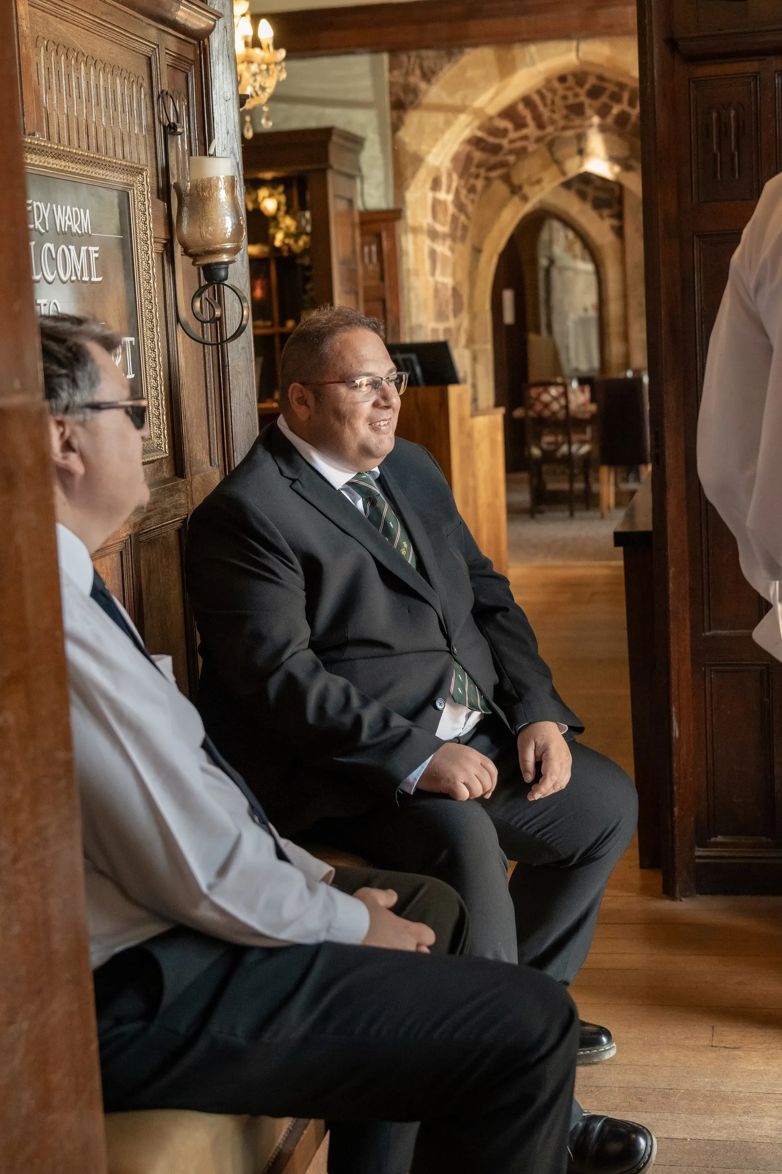 Two guests in suits waiting in the wood paneled hall