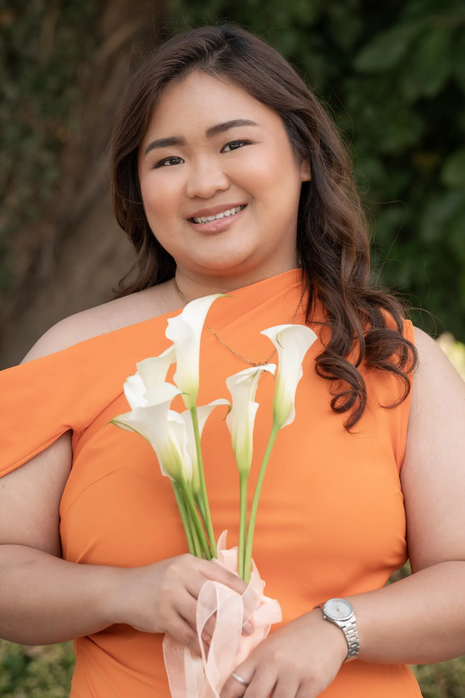 Bridesmaid in peach smiling with her bouquet of calla lilies