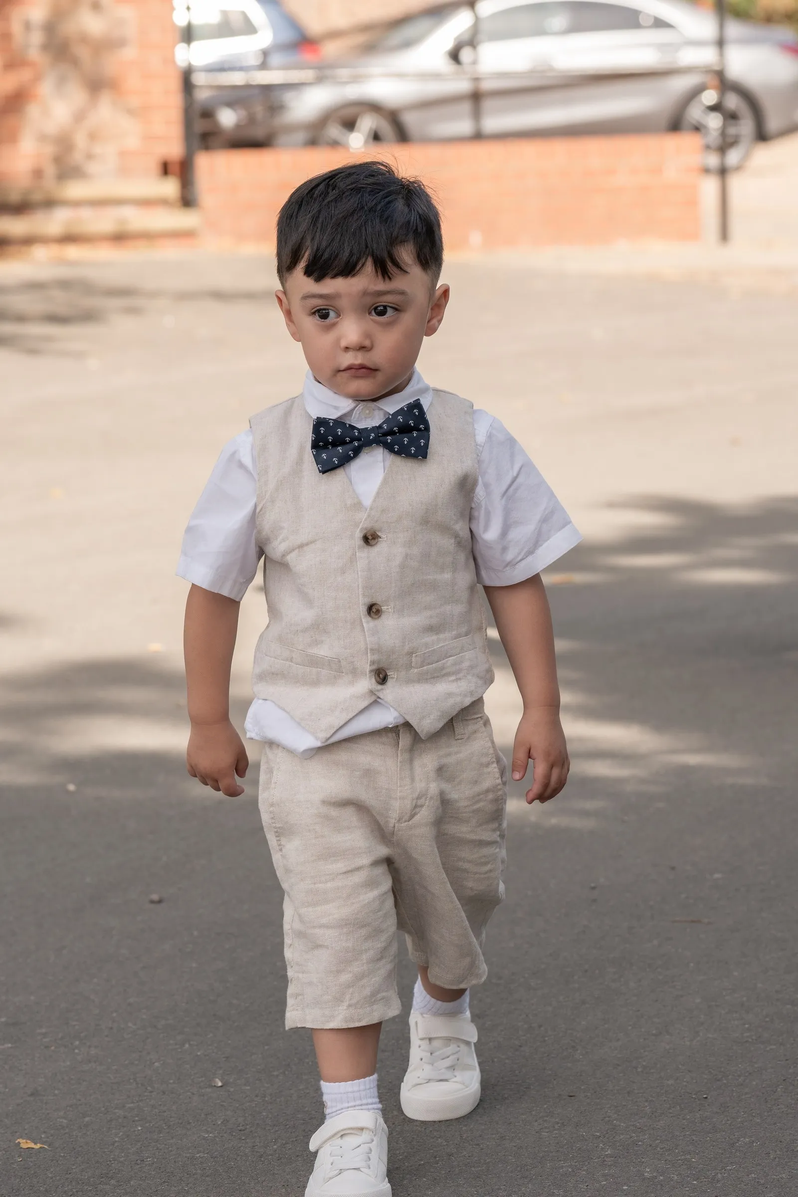 Mathelle's son in a linen vest and bow tie walking up the drive