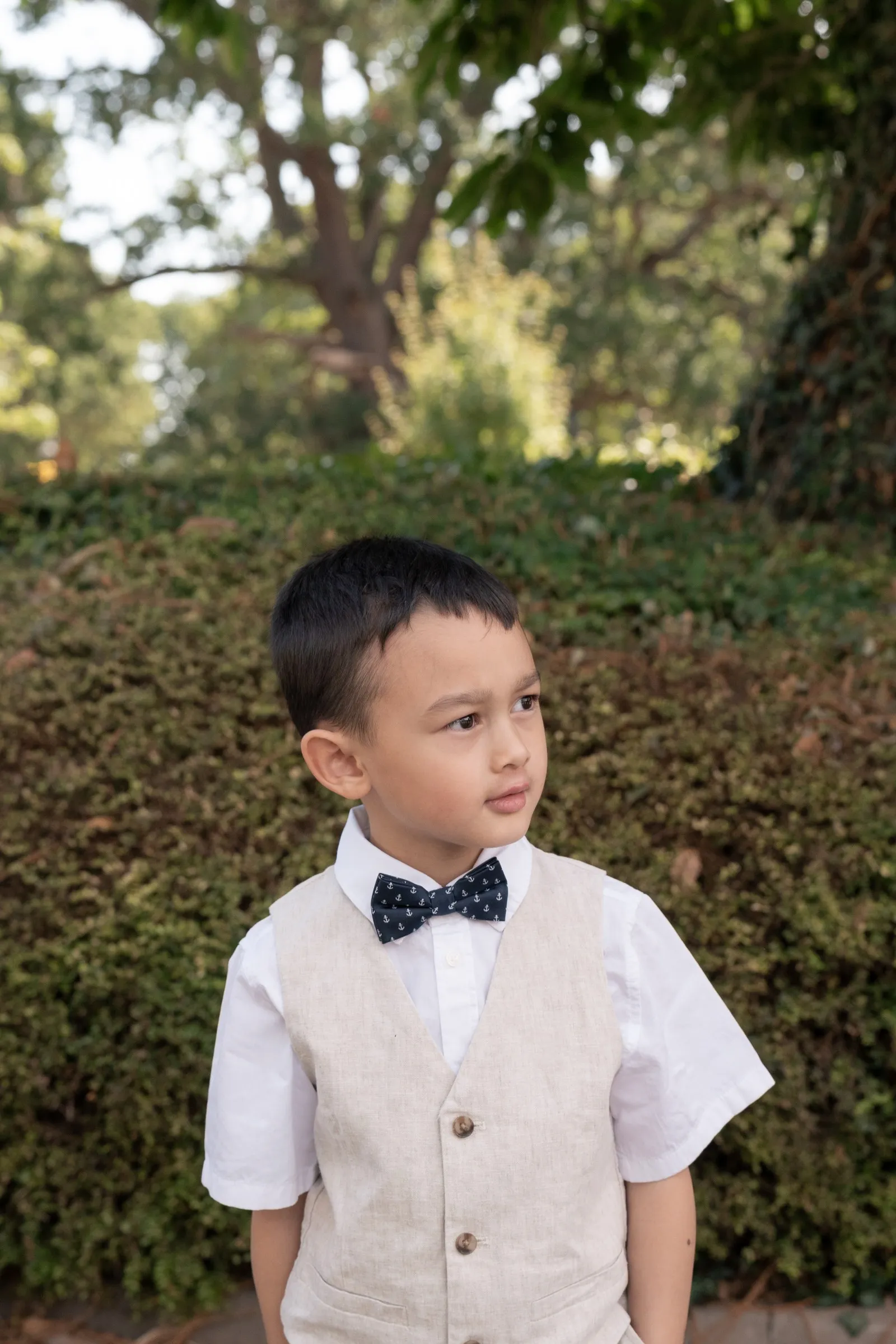 Mathelle's son in a linen vest standing by the hedges