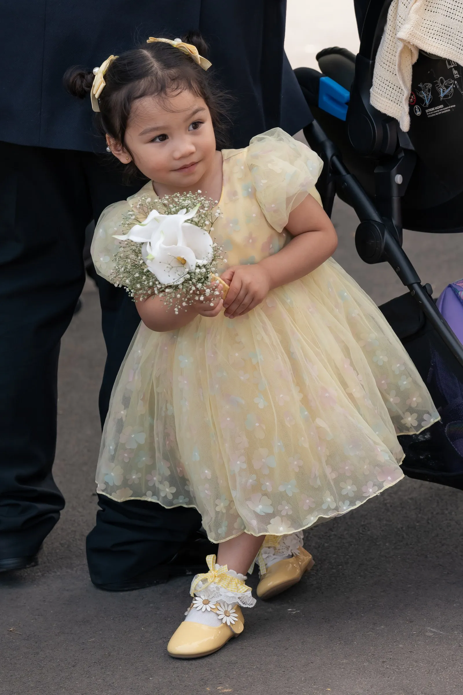 Flower girl in a pale yellow dress holding a small bouquet