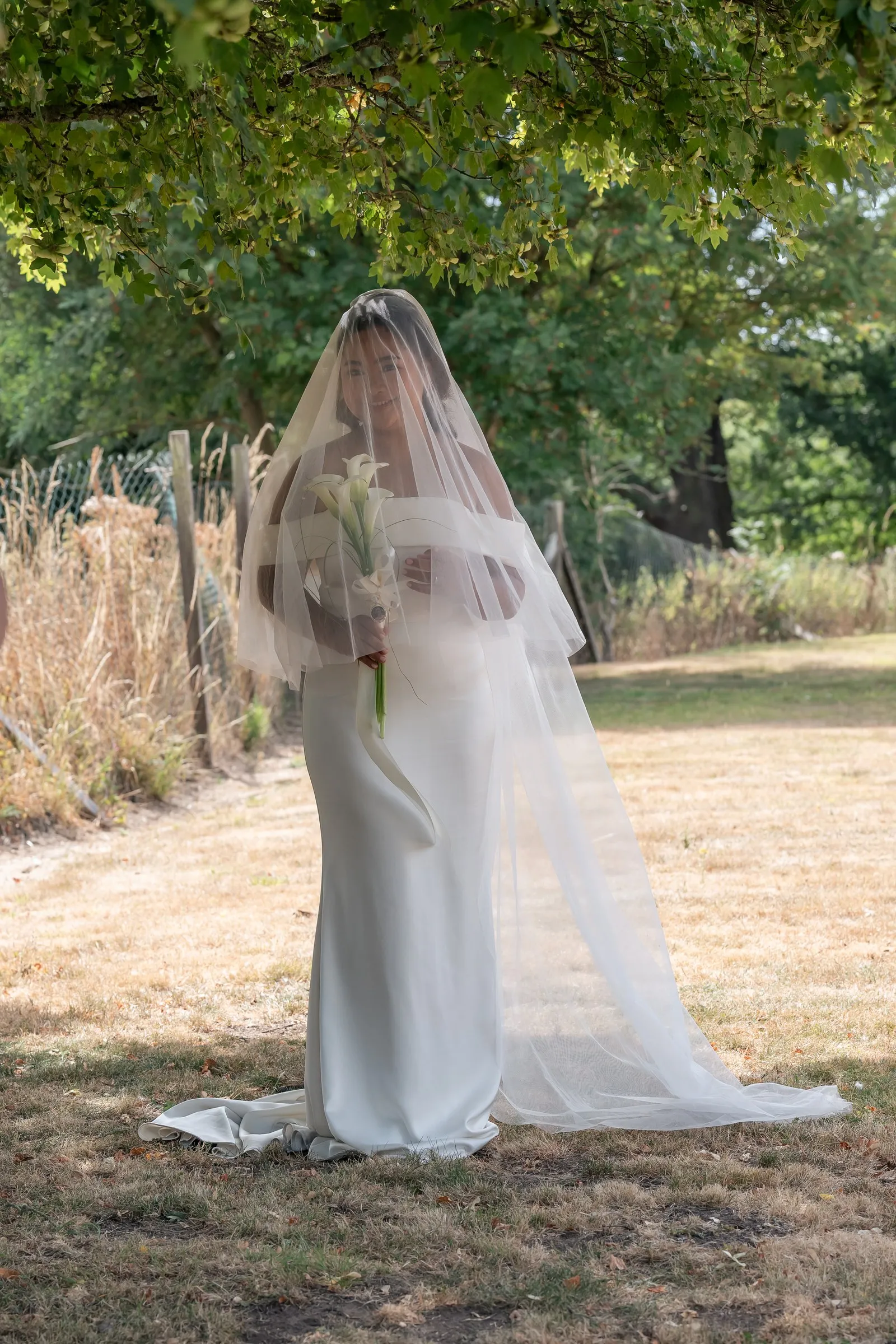 Full length portrait of Mathelle with her cathedral veil spread on the lawn