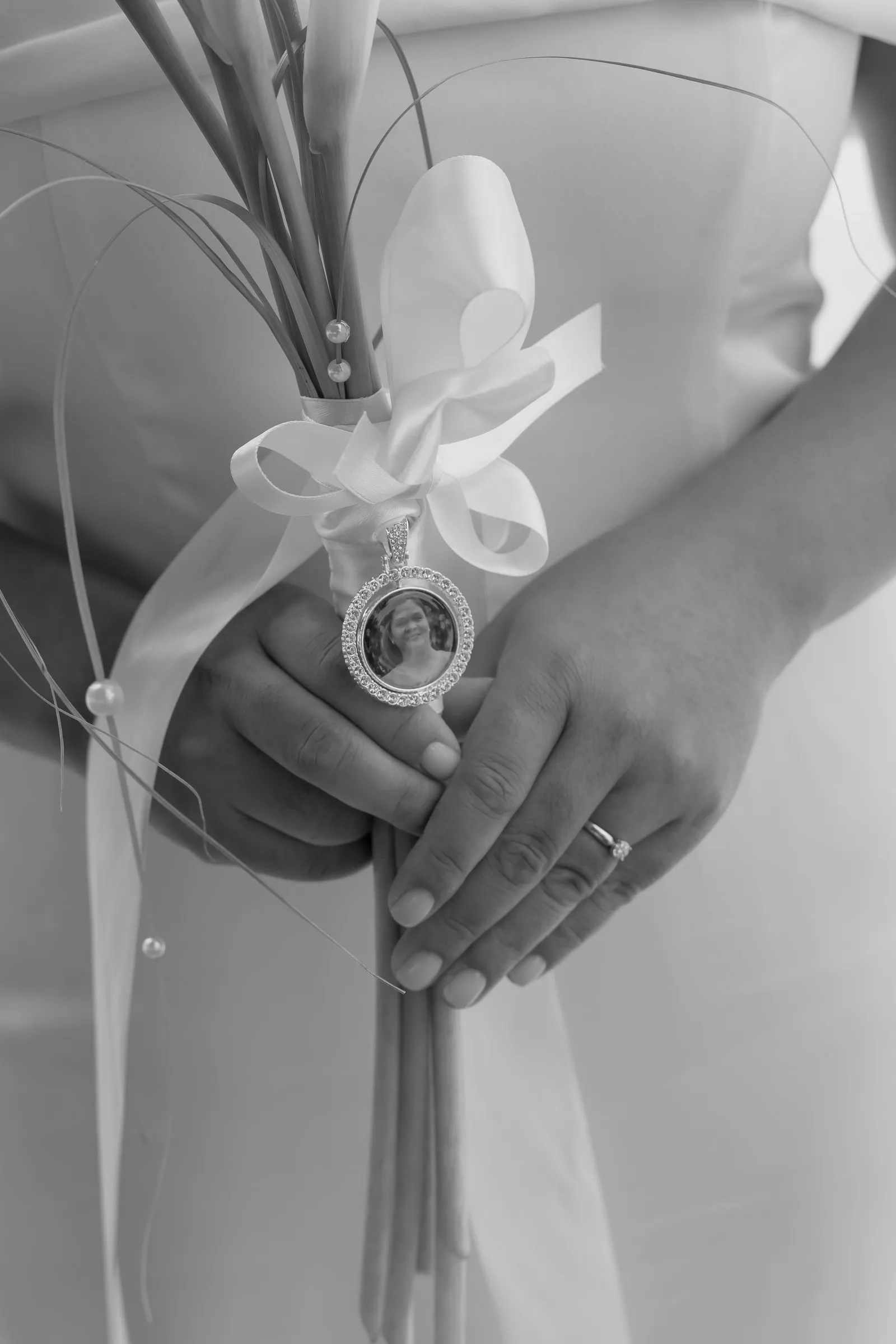 Black and white close-up of Mathelle's bouquet and keepsake locket charm