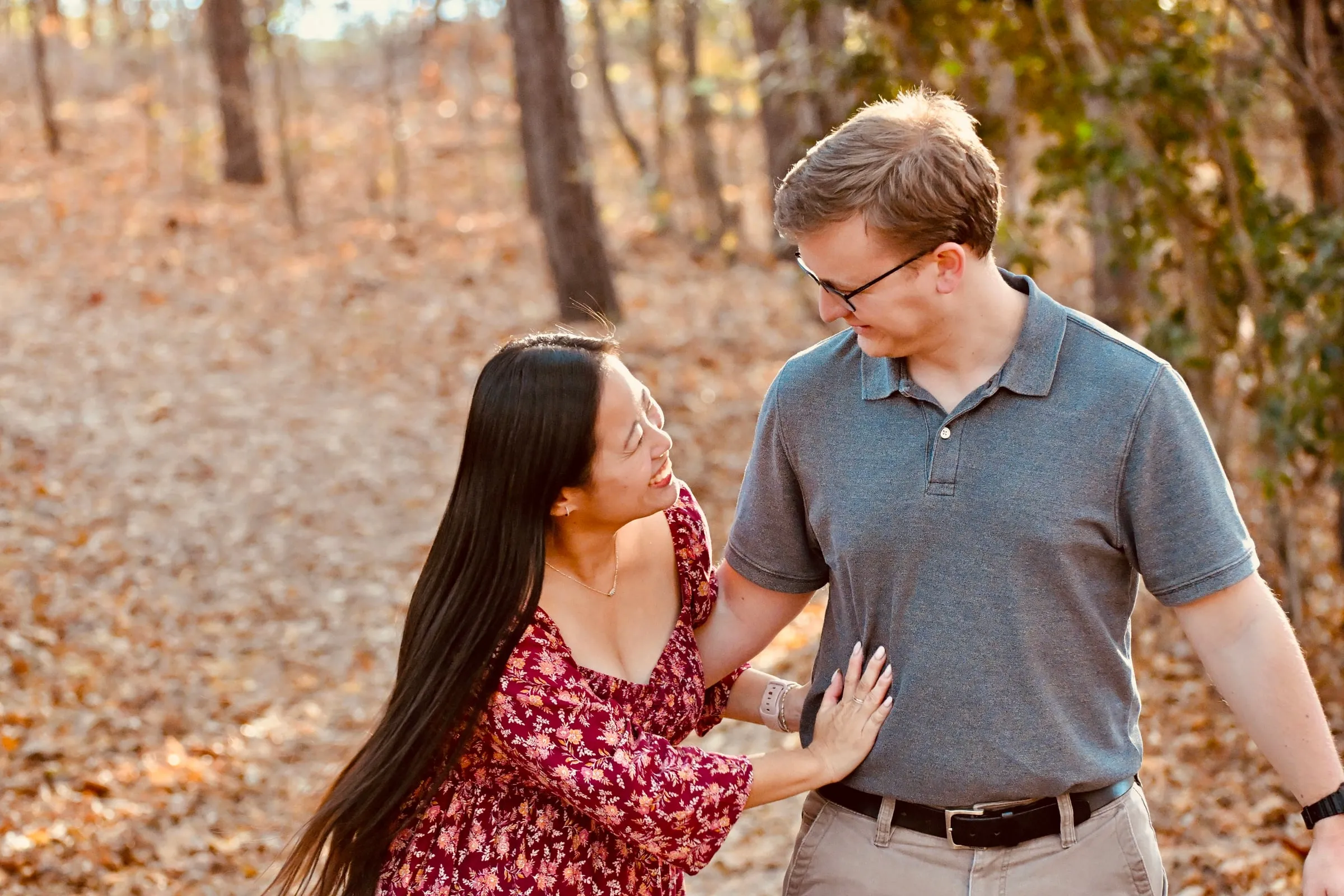 Mya laughing with her hand on Jacob's chest as they walk a leaf-covered trail