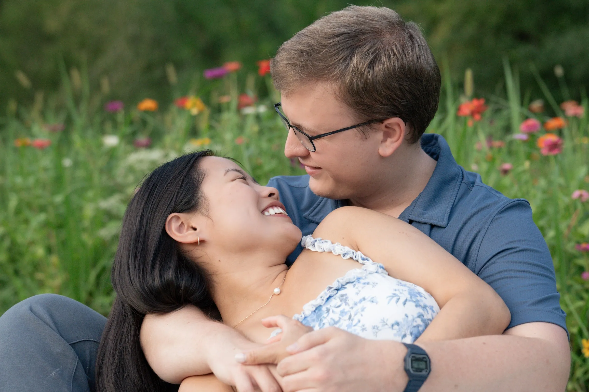 Mya lying back in Jacob's lap, laughing, with wildflowers behind them