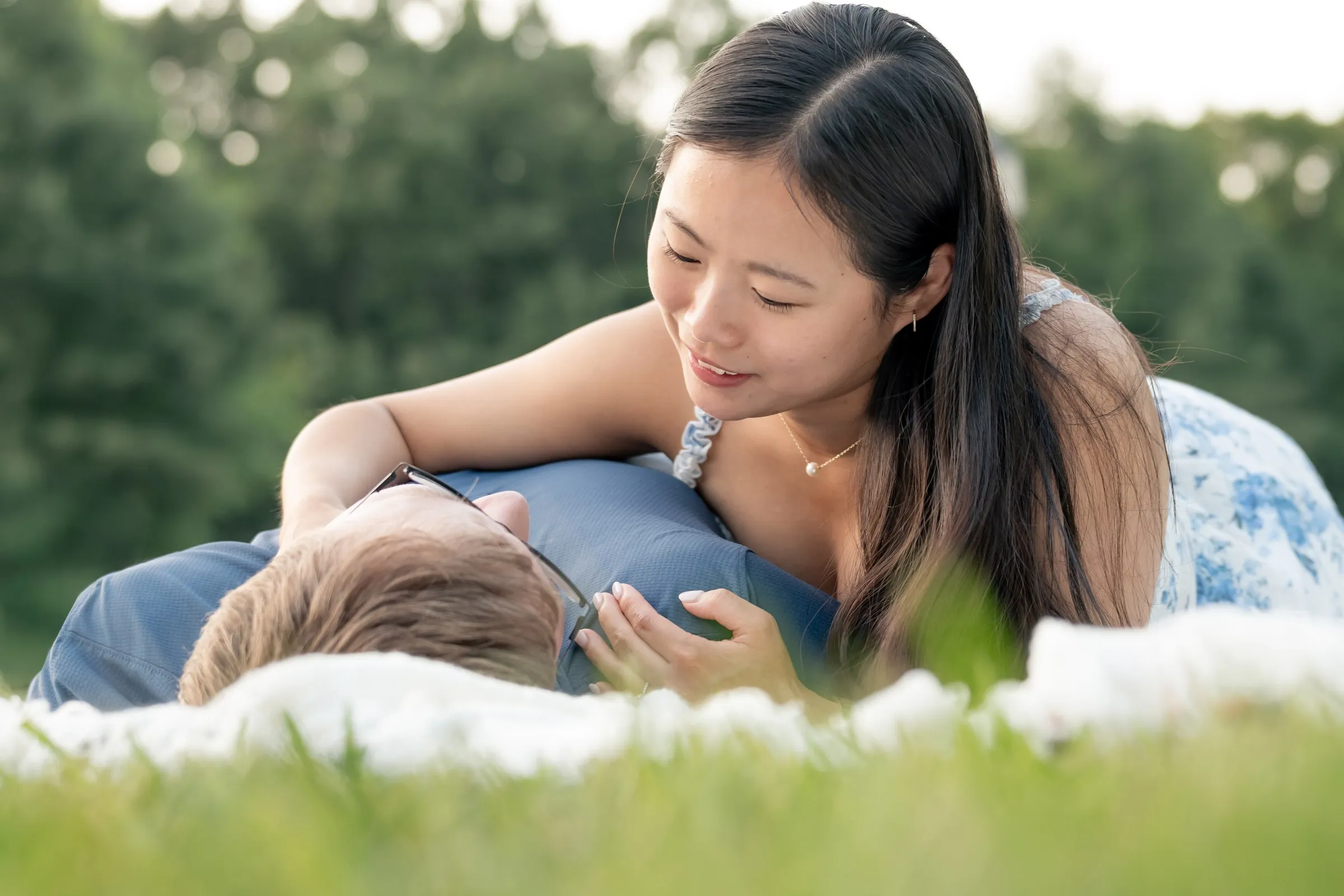 Low angle view of Mya leaning over Jacob on a blanket in the grass