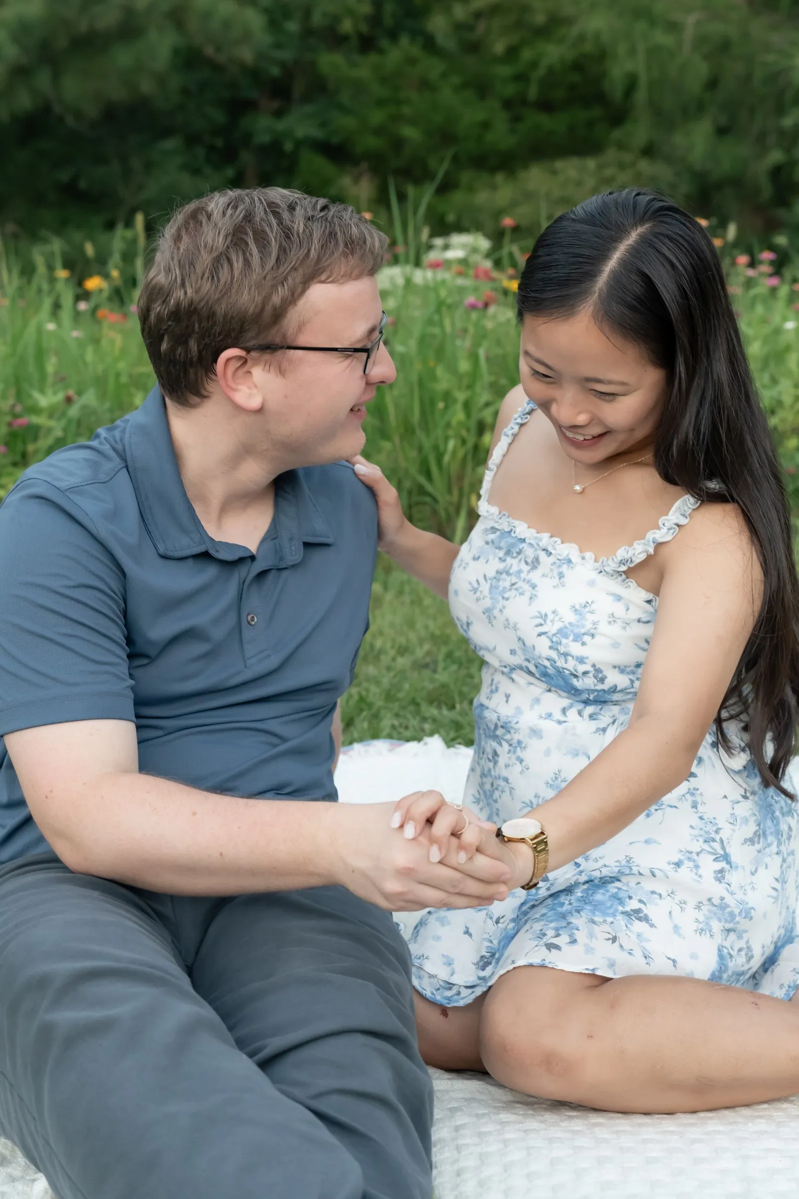 Mya and Jacob seated on the blanket holding hands and smiling at the camera