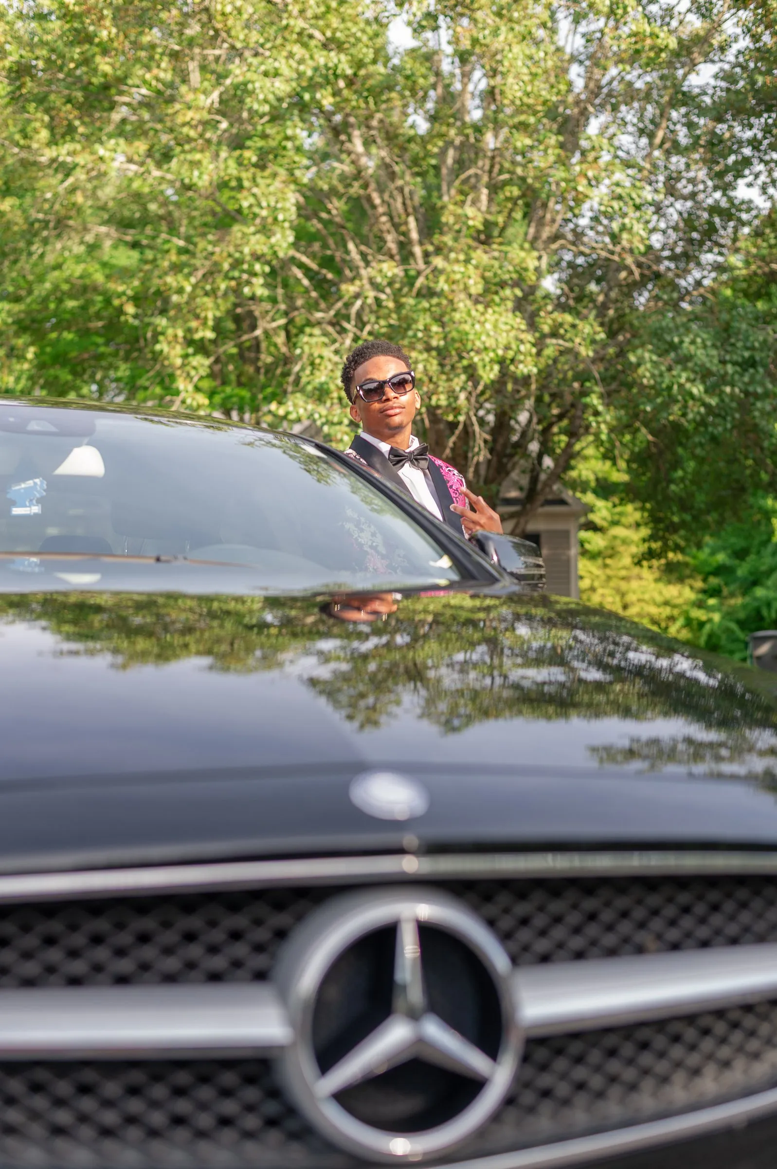 The Mercedes grille in sharp focus with him soft in the background