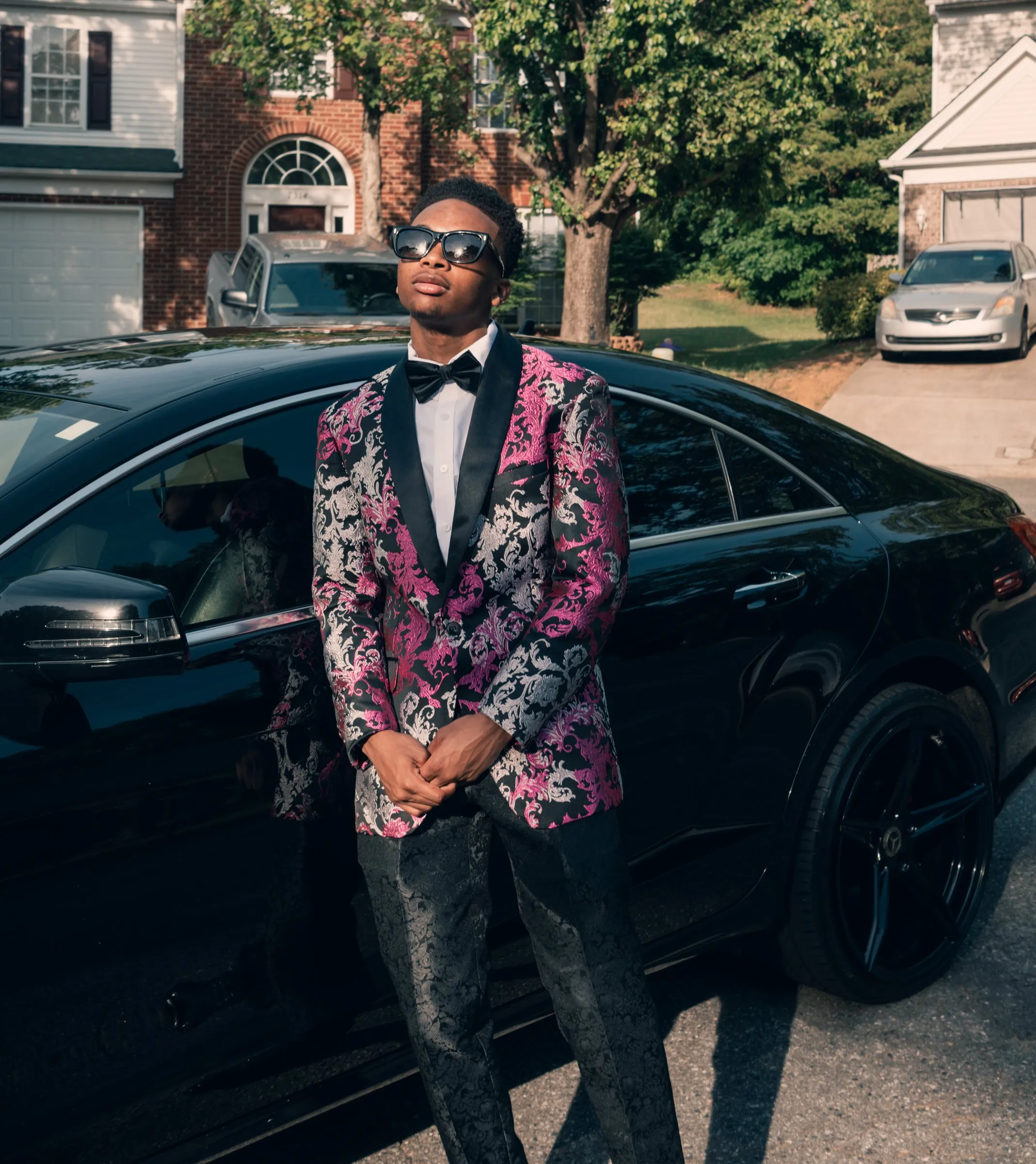 He leans on a black Mercedes in golden evening light