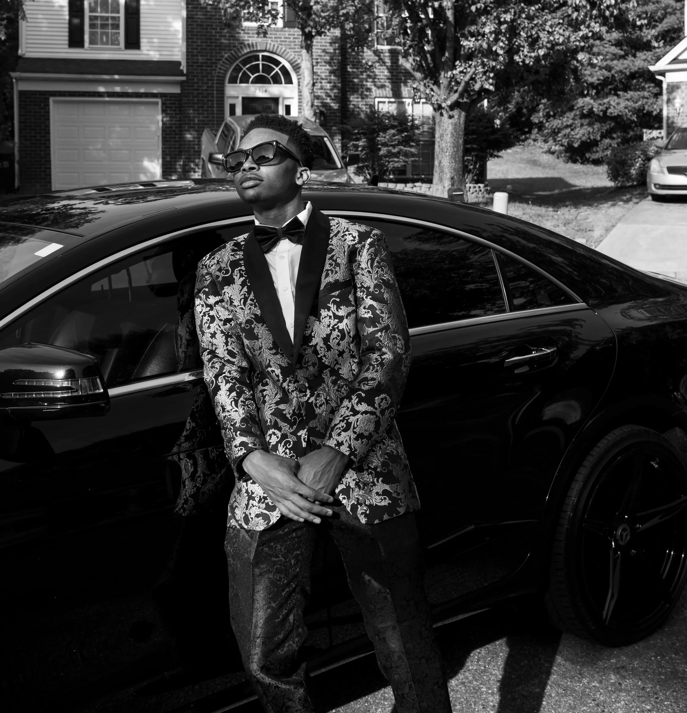 Black and white photograph of him leaning on the black Mercedes