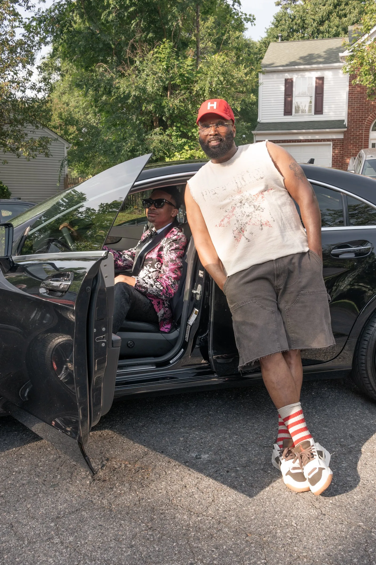 A man in a red cap stands by the open driver's door