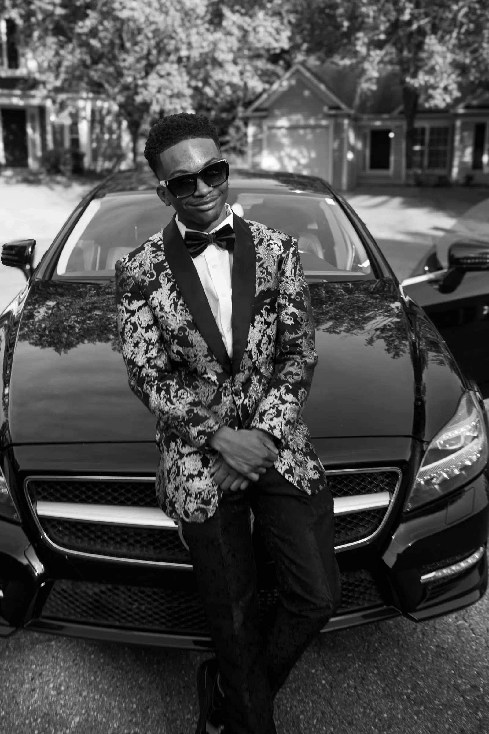 Black and white photograph of him sitting on the Mercedes hood