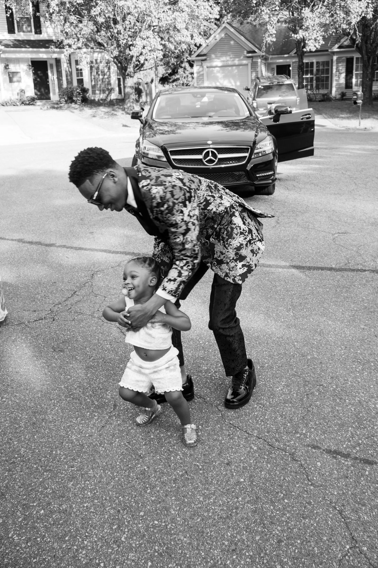 Black and white photograph of him walking a toddler down the street