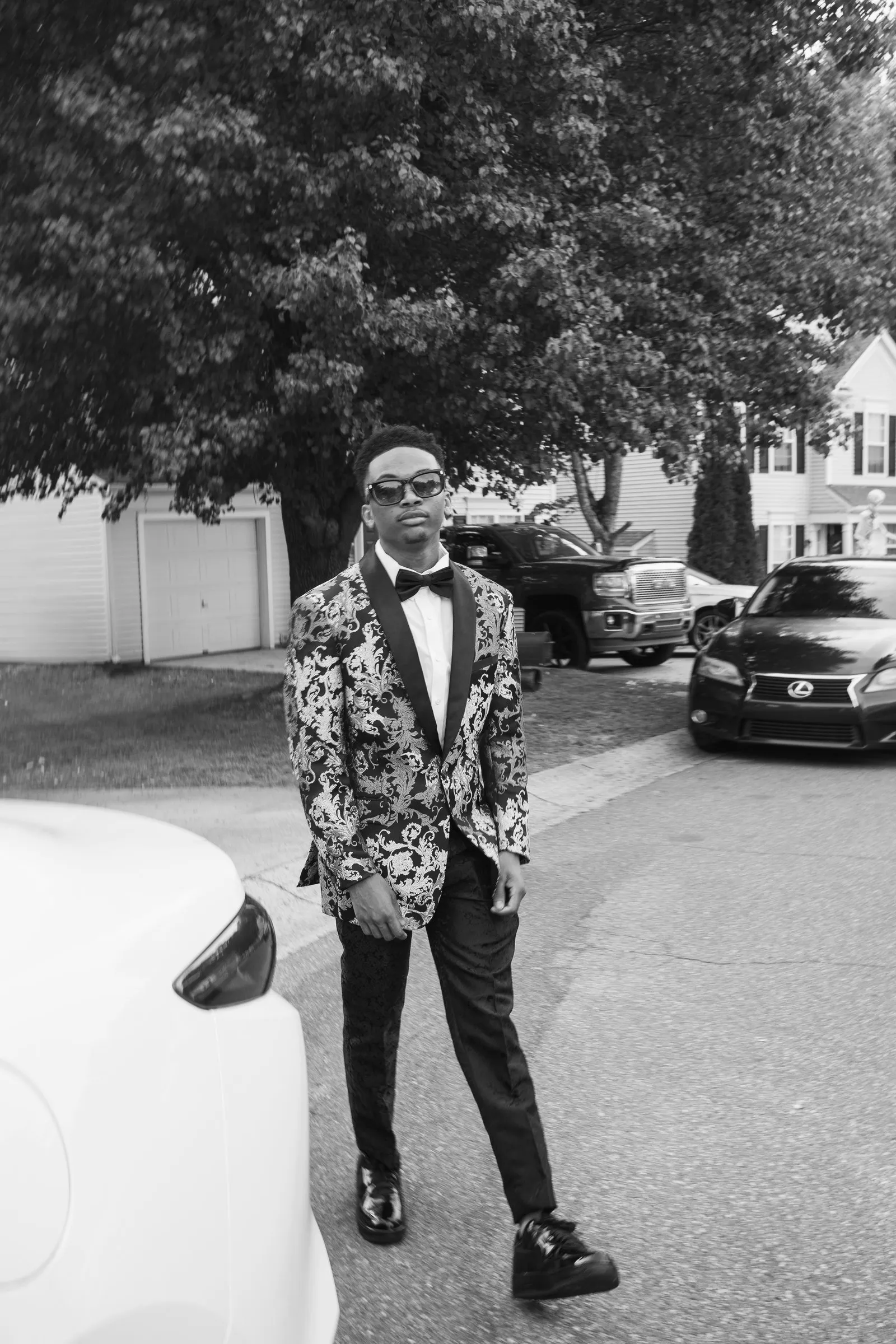 Black and white photograph of him standing in the street, a car parked behind him
