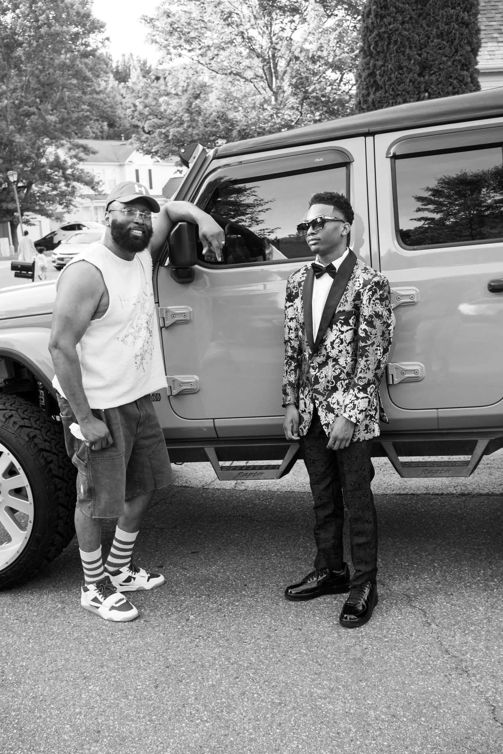 Black and white photograph of him with a man in a cap beside the Jeep