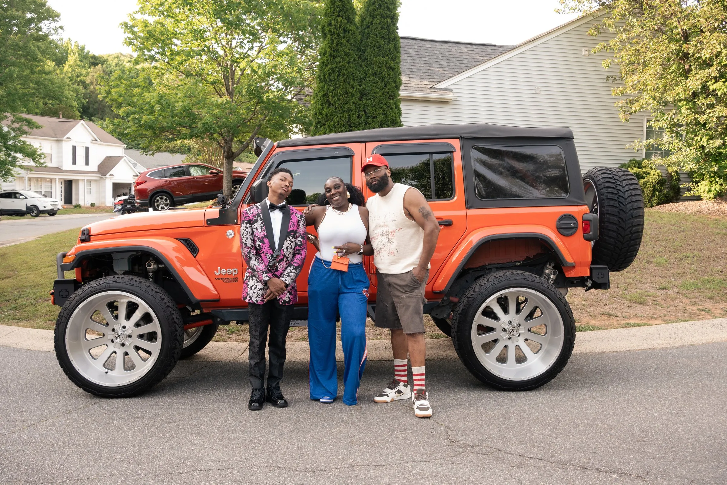 Three across in front of the orange Jeep Wrangler