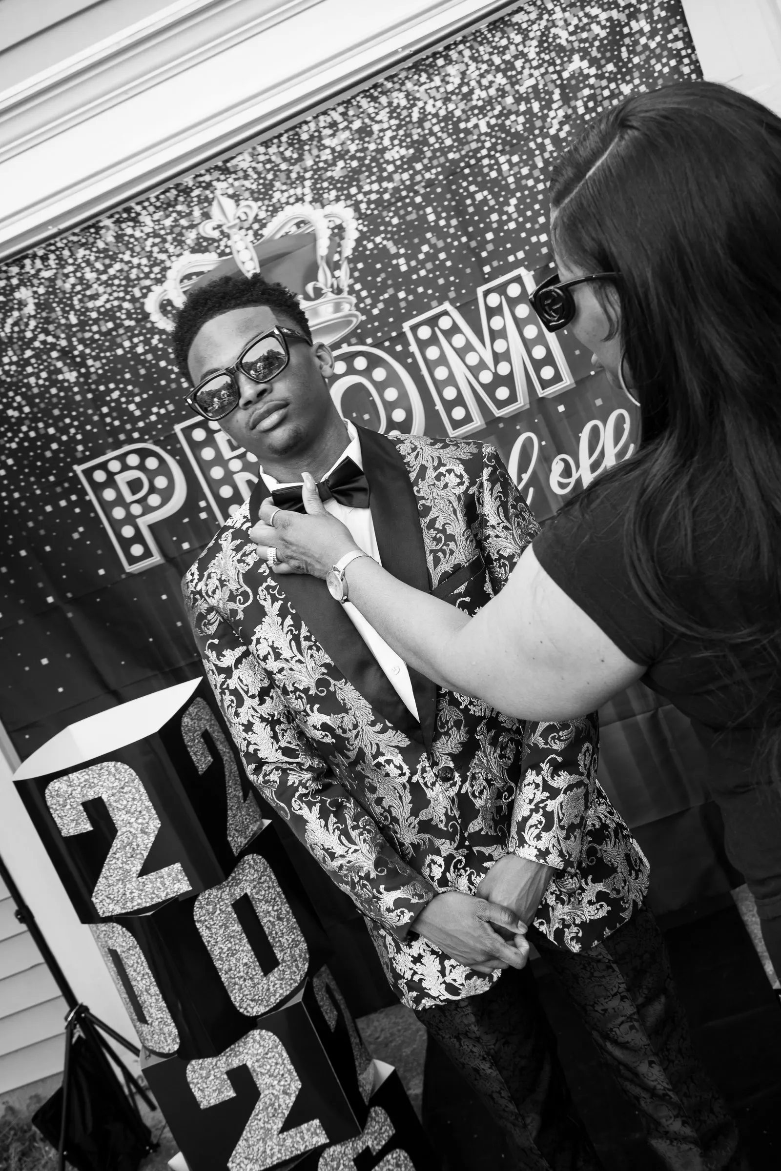 Black and white photograph of his bow tie being straightened beside the 2026 blocks