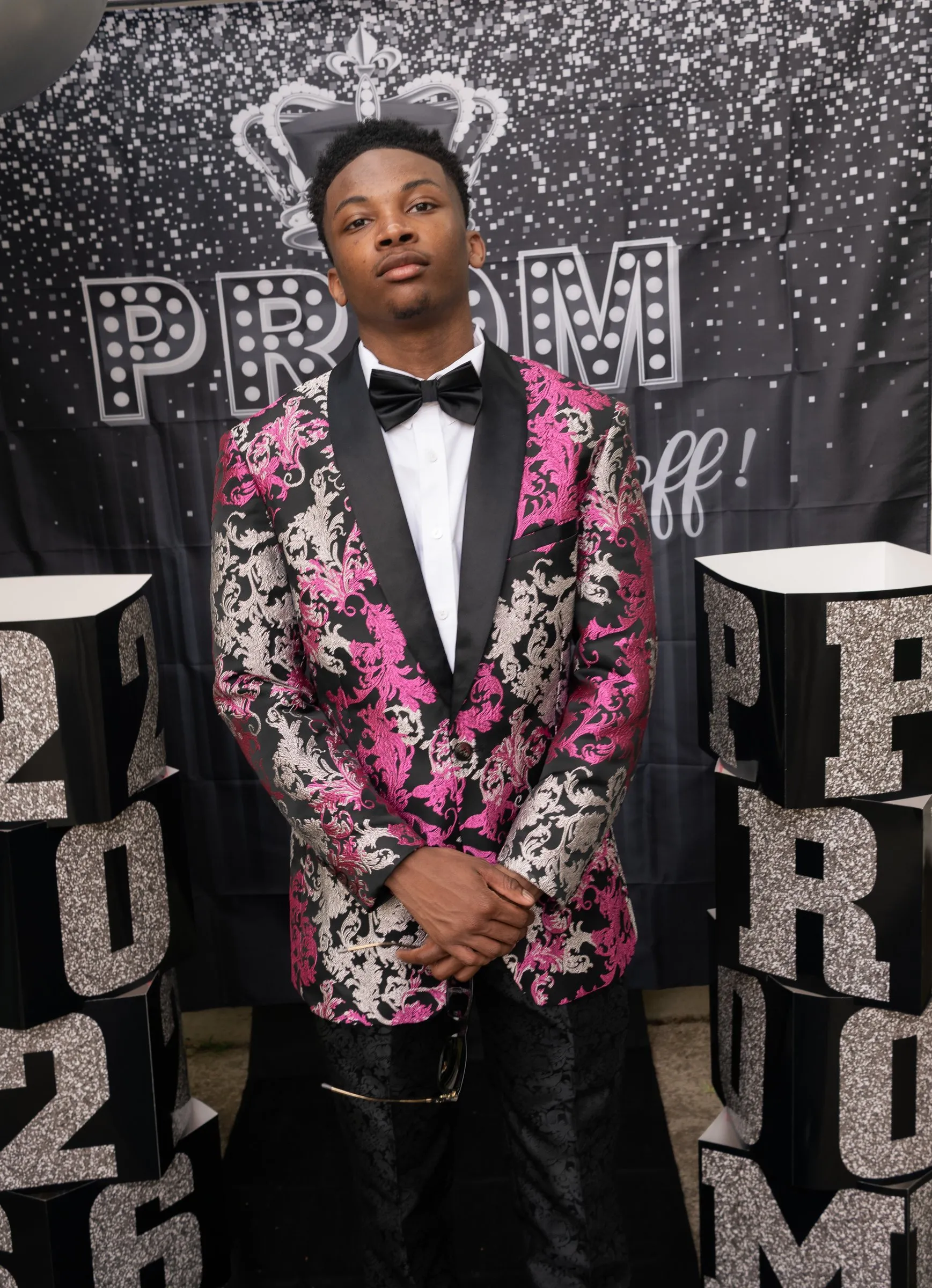 Standing prom portrait without sunglasses between the 2026 and PROM glitter blocks