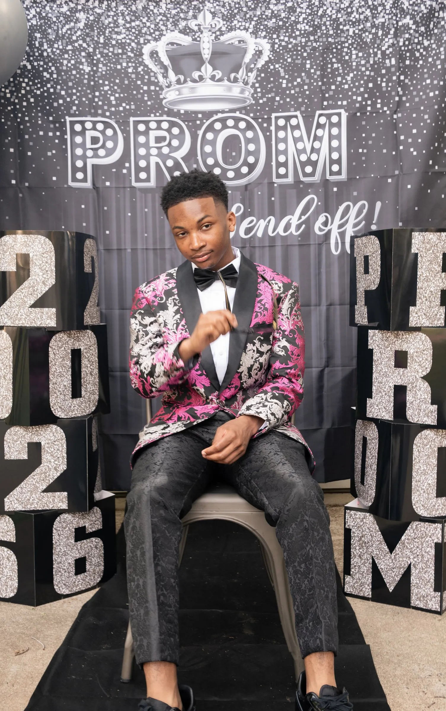 Seated portrait between the glitter blocks, one hand resting on his knee