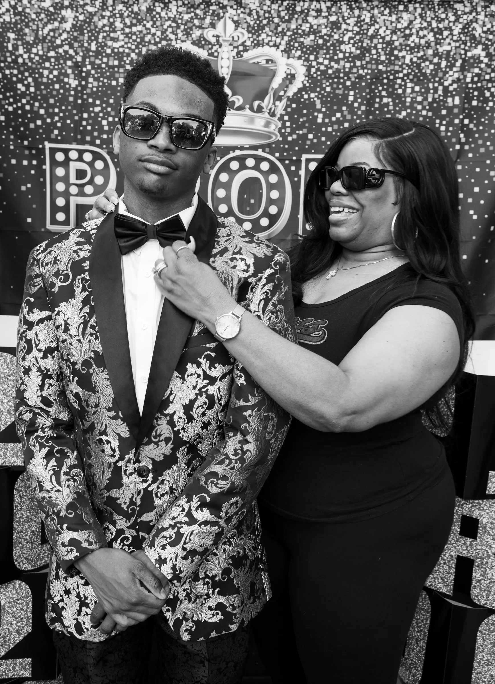 Black and white photograph of a woman fixing his bow tie as they pose together