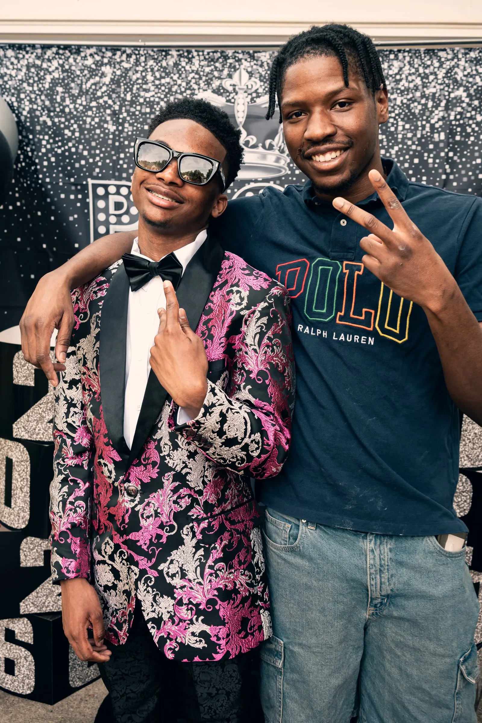 He laughs with a friend in a Polo shirt at the backdrop