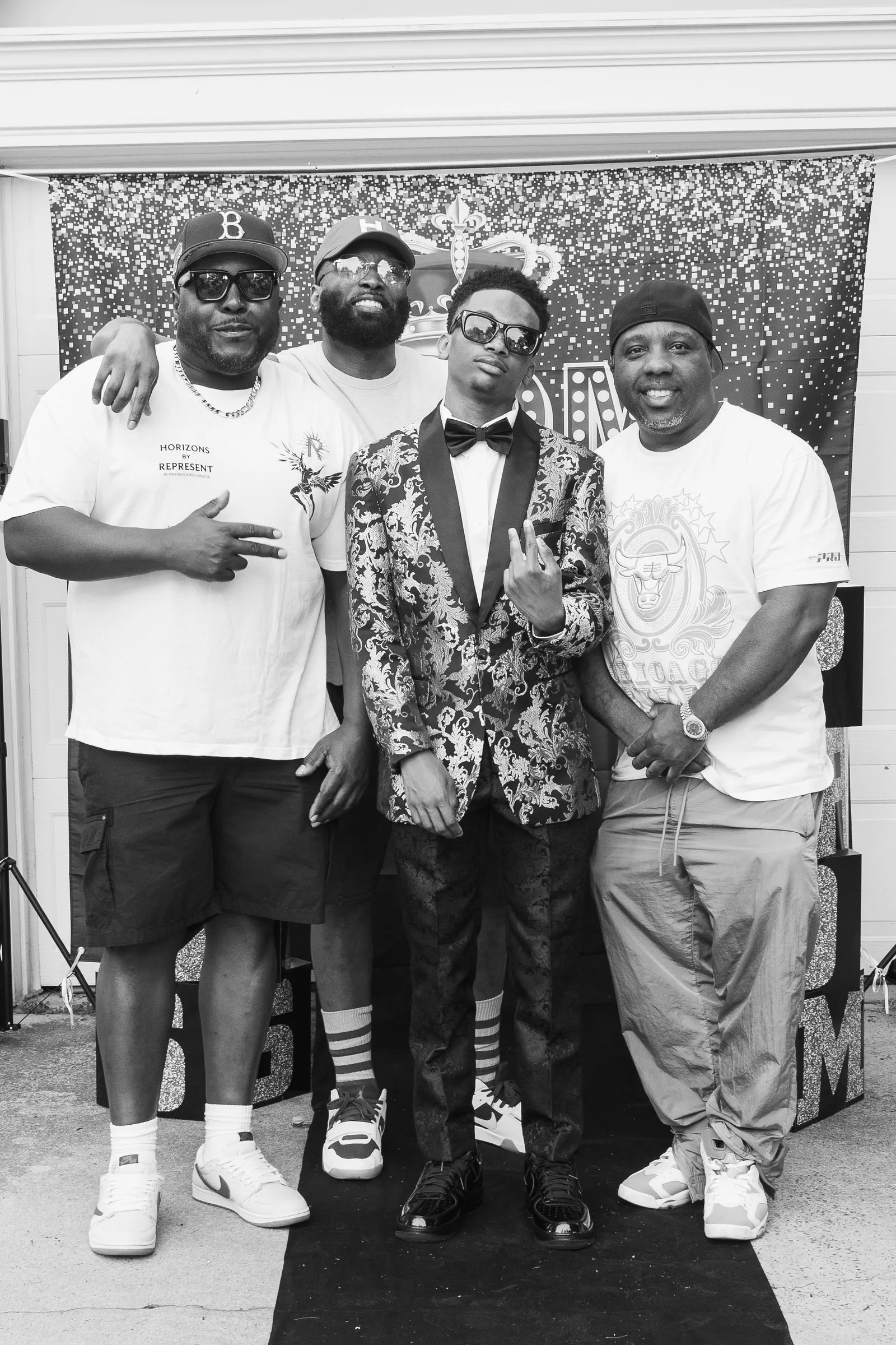 Black and white photograph of him posing with three men at the backdrop