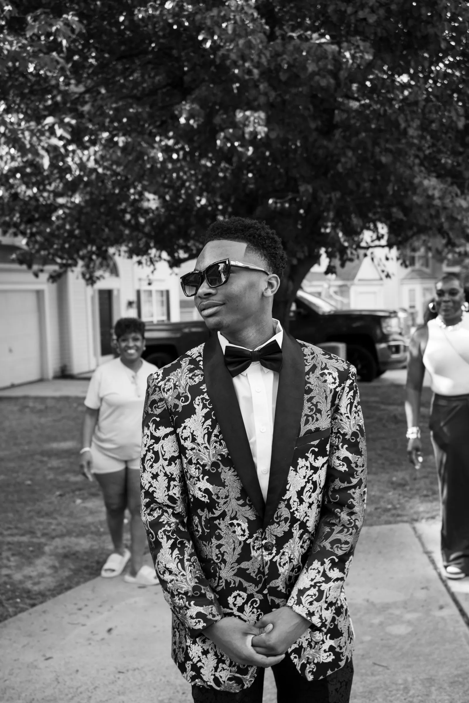 Black and white portrait on the front walk with guests gathering behind him