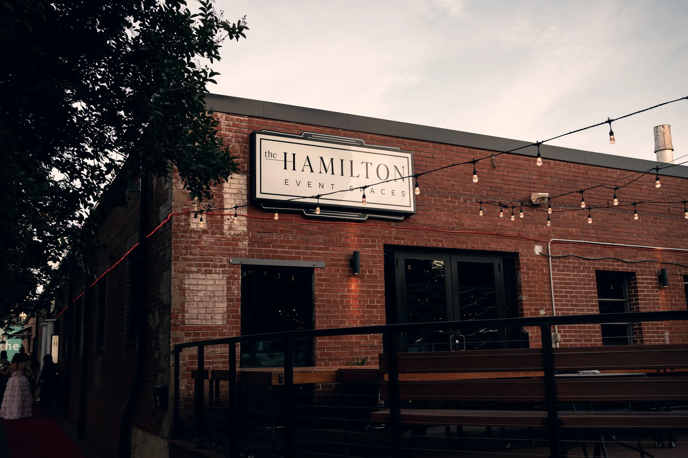The Hamilton's brick building and string lights at dusk
