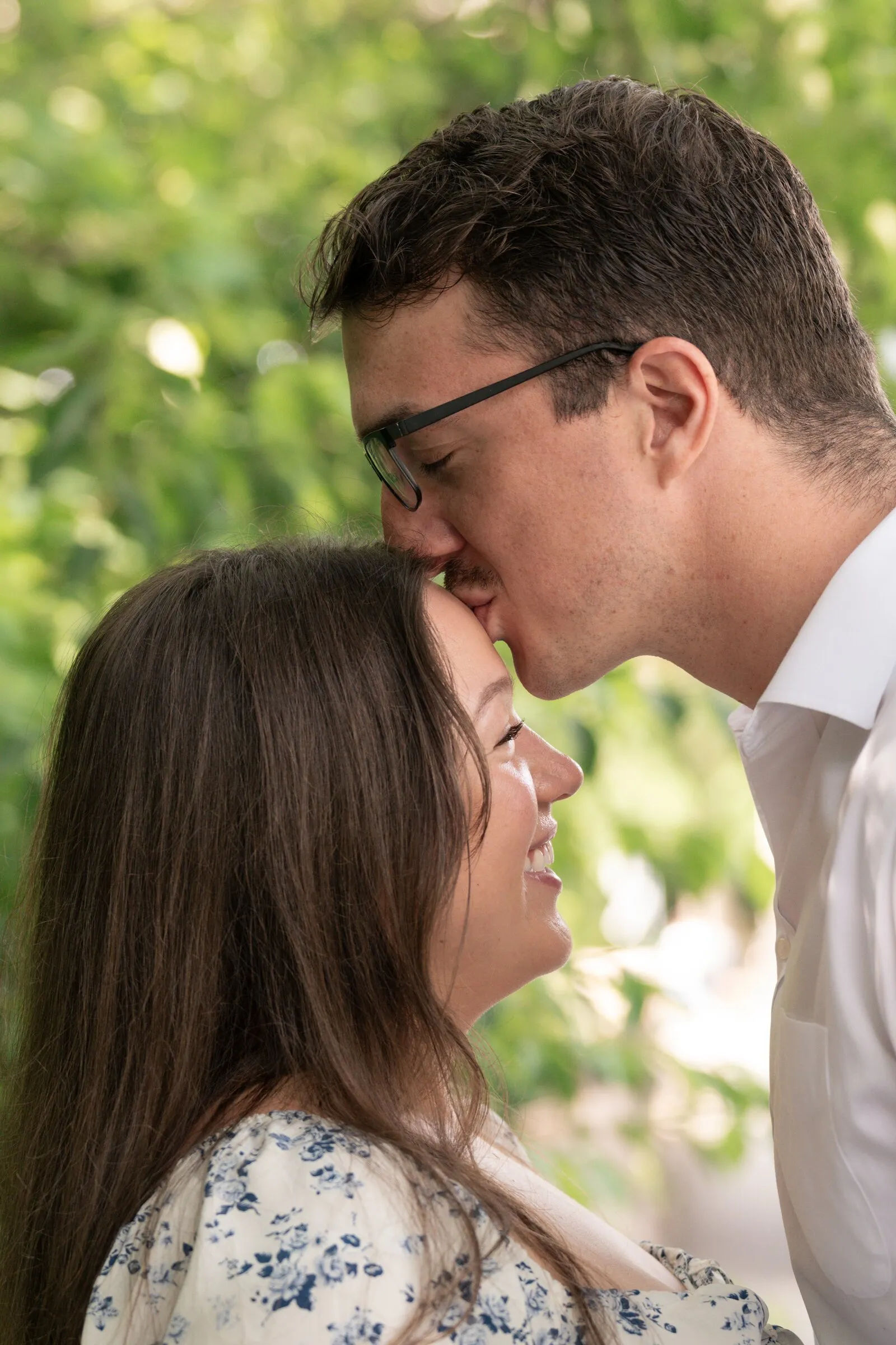 Spencer kissing Kayla's forehead as she smiles, leaves glowing behind them