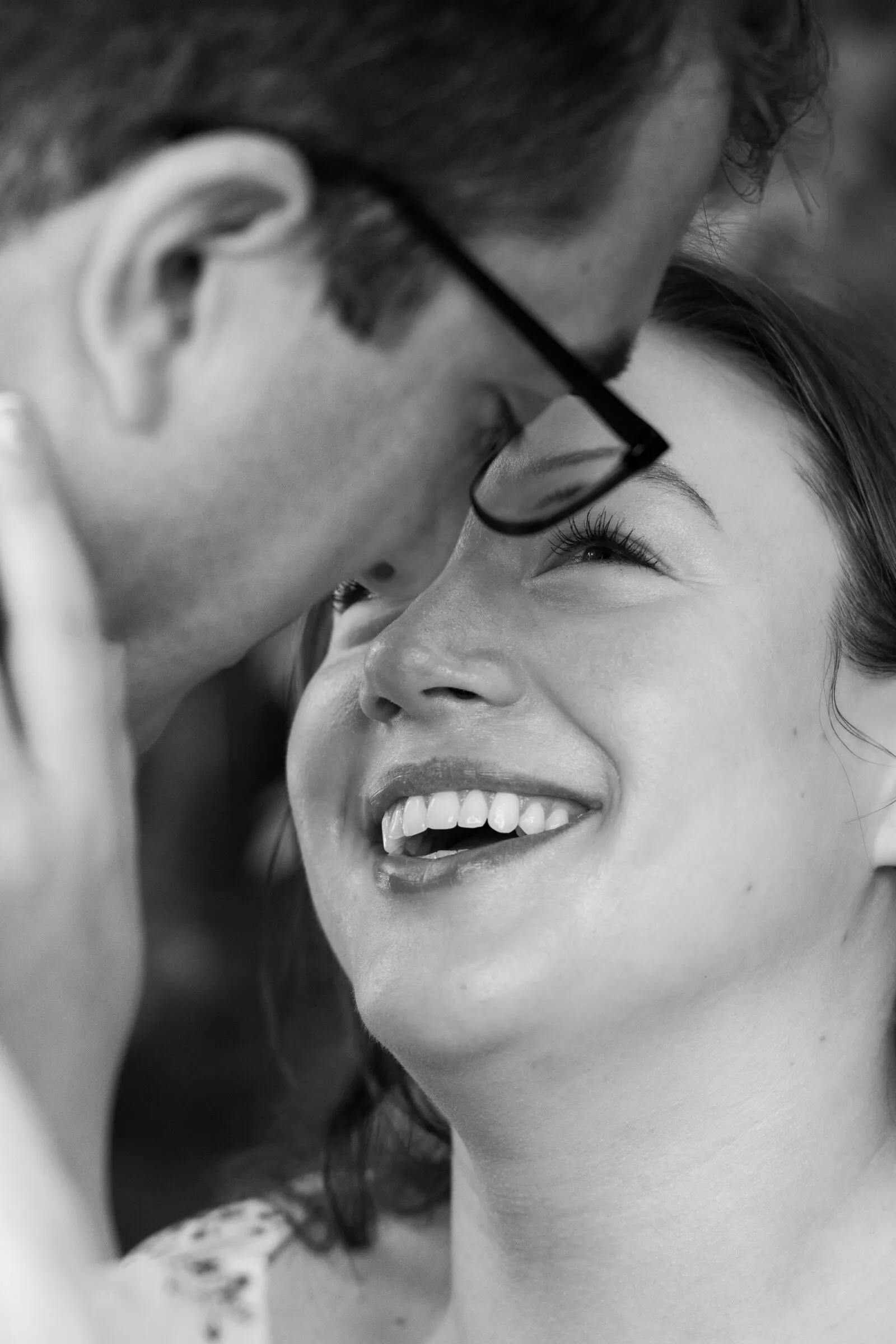 Black and white close-up of Kayla's wide smile as Spencer leans in