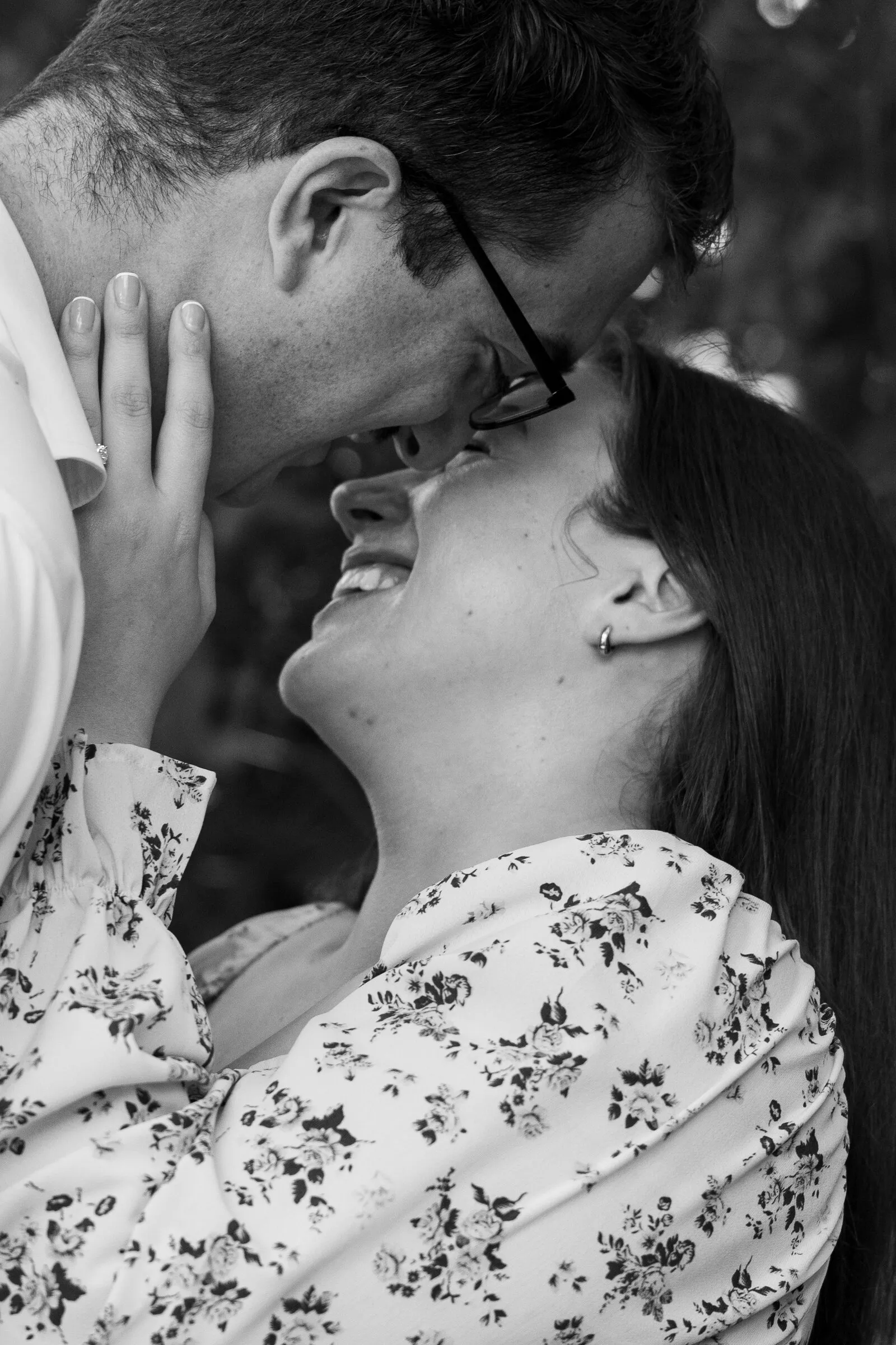 Black and white photograph of Kayla holding Spencer's face and smiling up at him