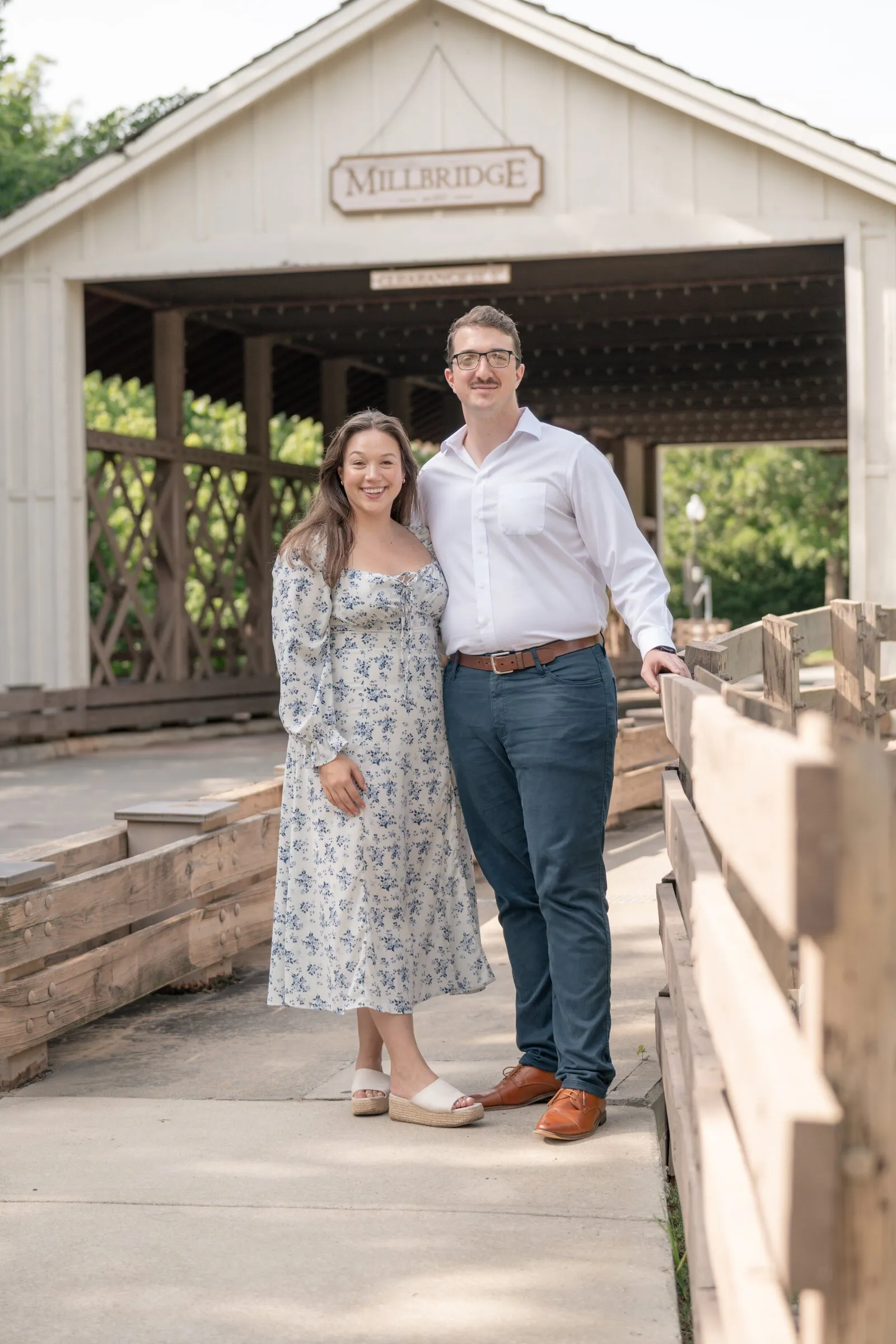 Spencer and Kayla standing beside the wooden rail at the entrance to the Millbridge covered bridge
