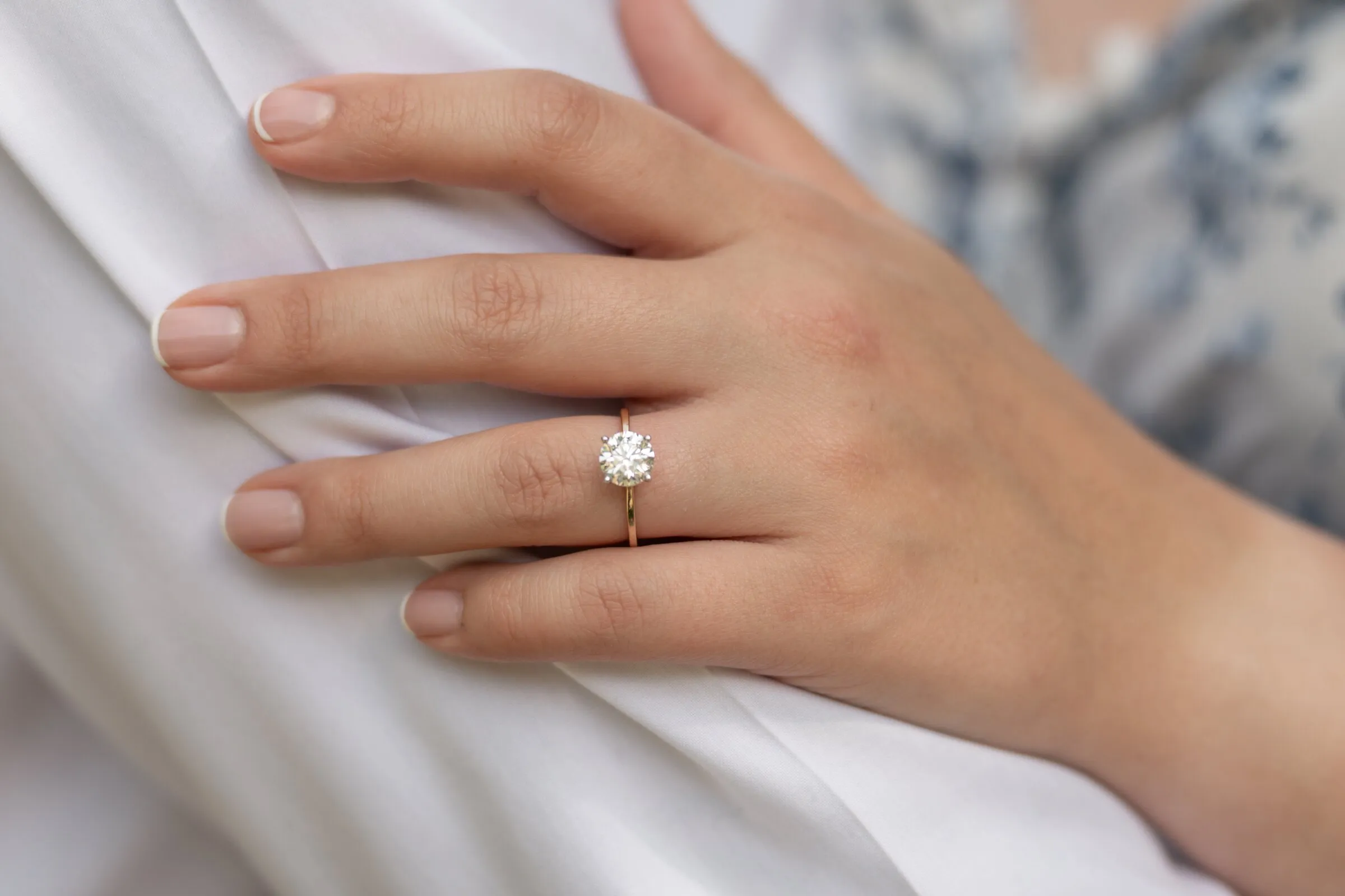 Kayla's solitaire engagement ring on a gold band, her hand resting on Spencer's white shirt at Millbridge in Waxhaw, NC, edited in the Loerop Signature