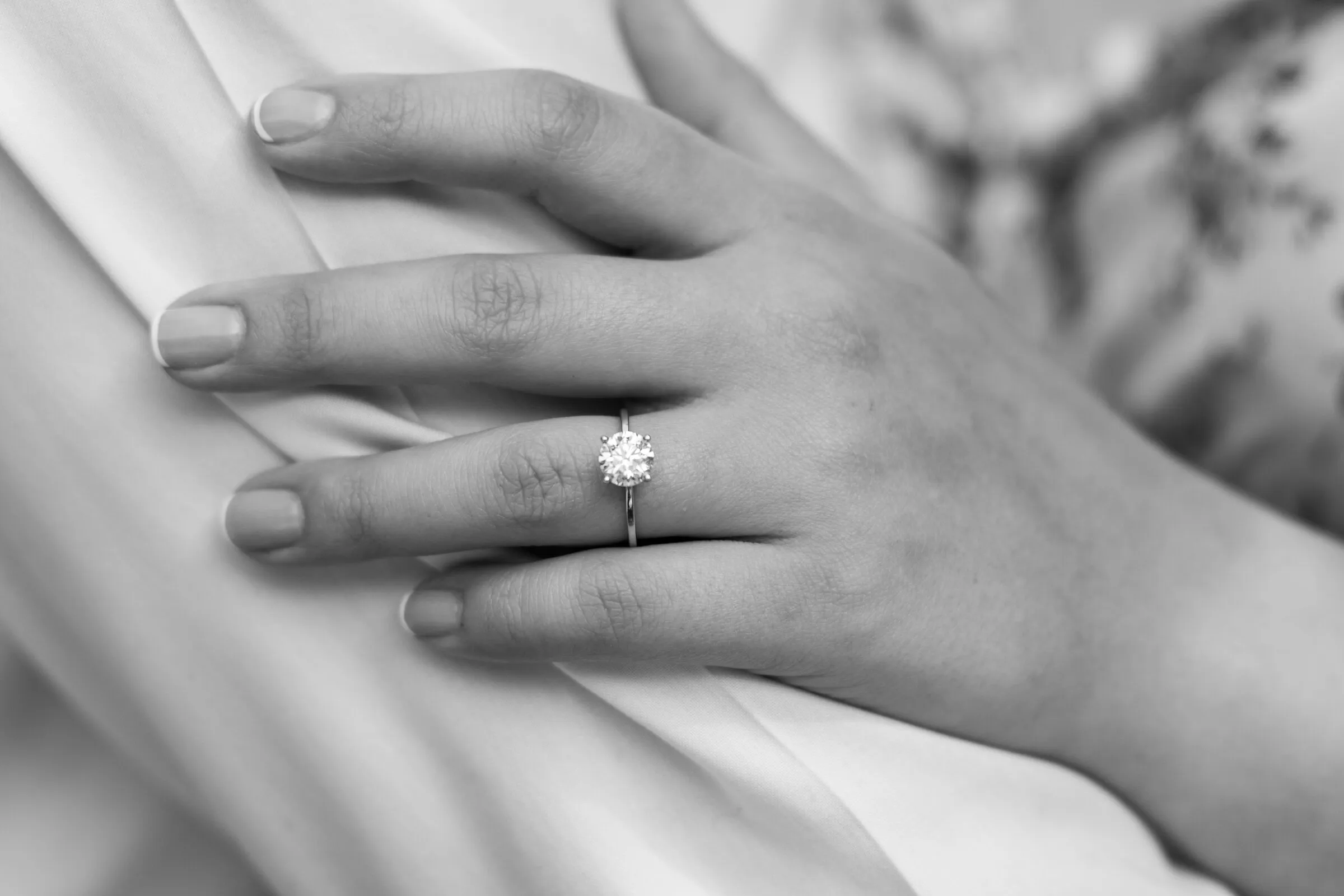 Black and white detail of Kayla's hand and engagement ring against Spencer's shirt