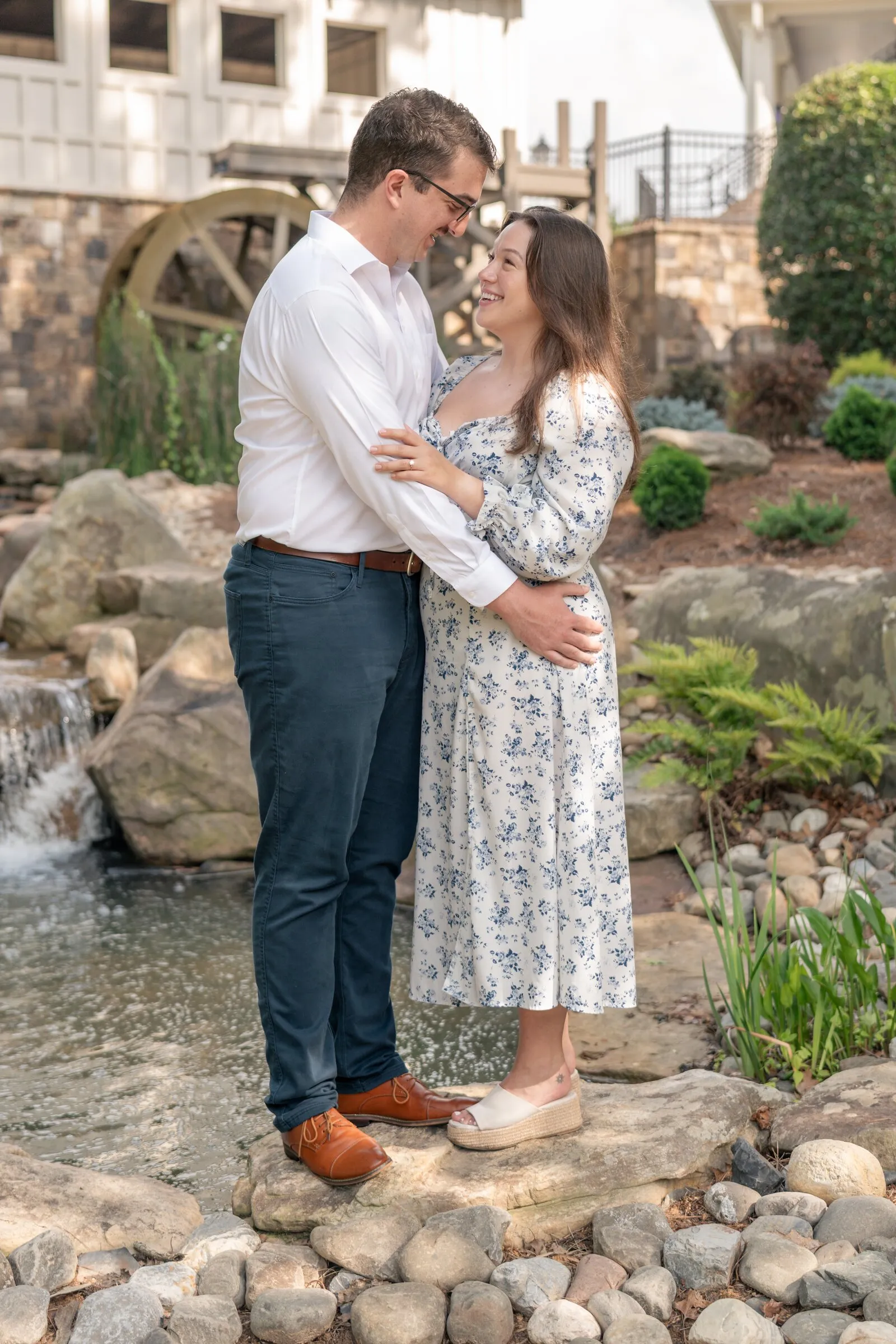 Spencer and Kayla embracing on the stones of the waterfall below the mill