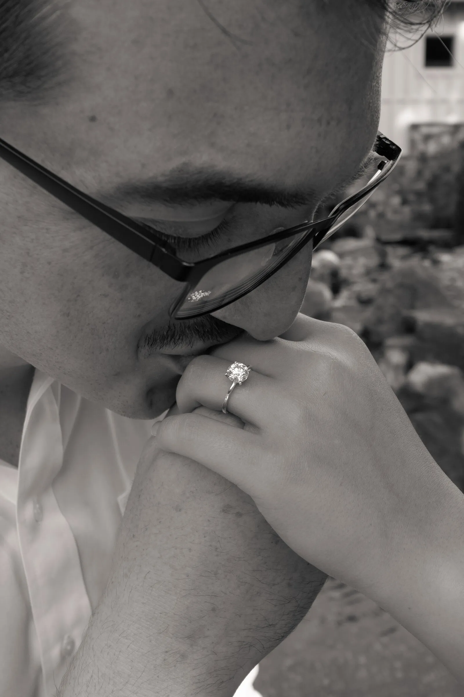 Black and white close-up of Spencer kissing Kayla's ring hand